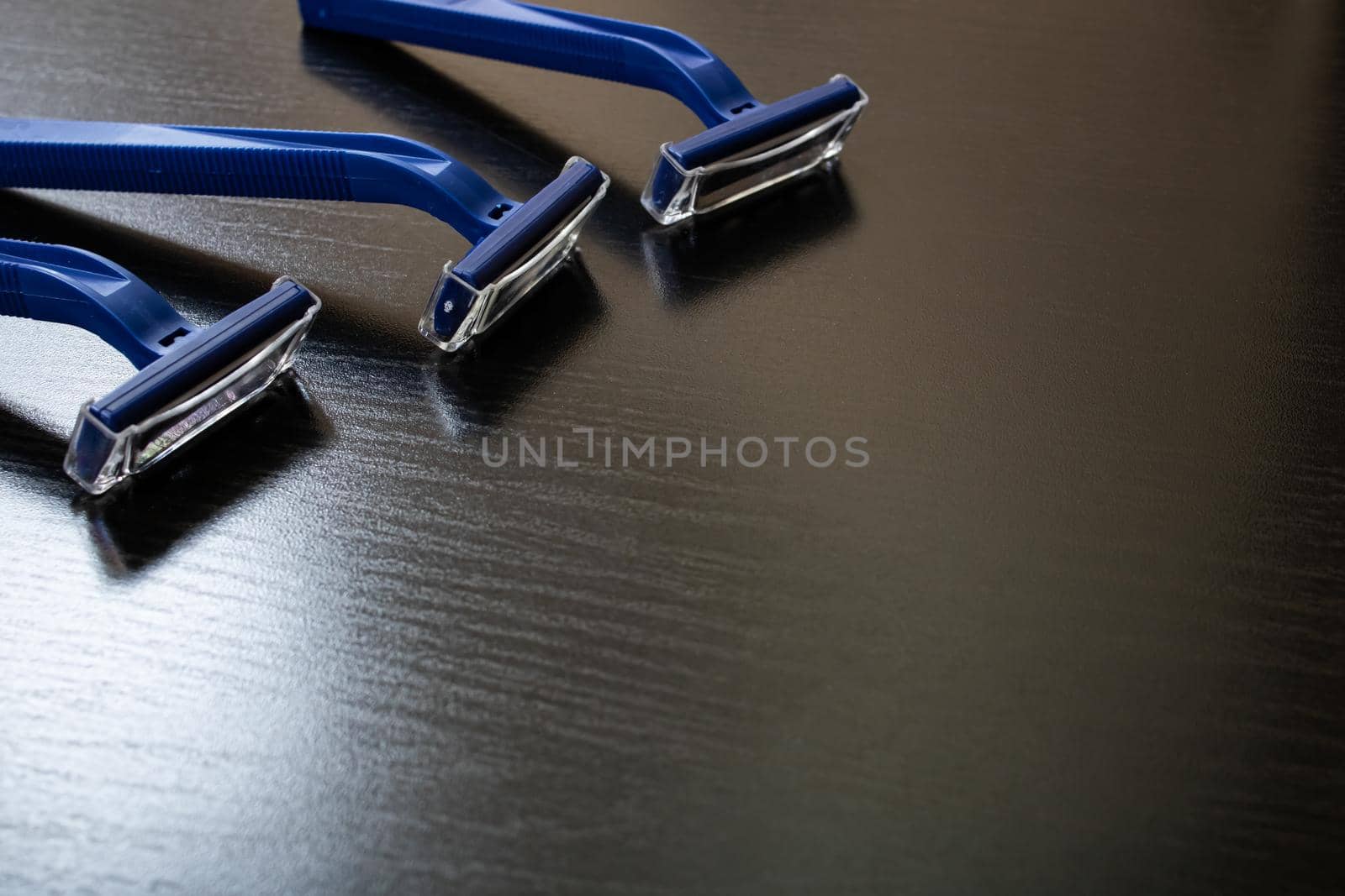 Three blue razors on a wooden background by Vera1703