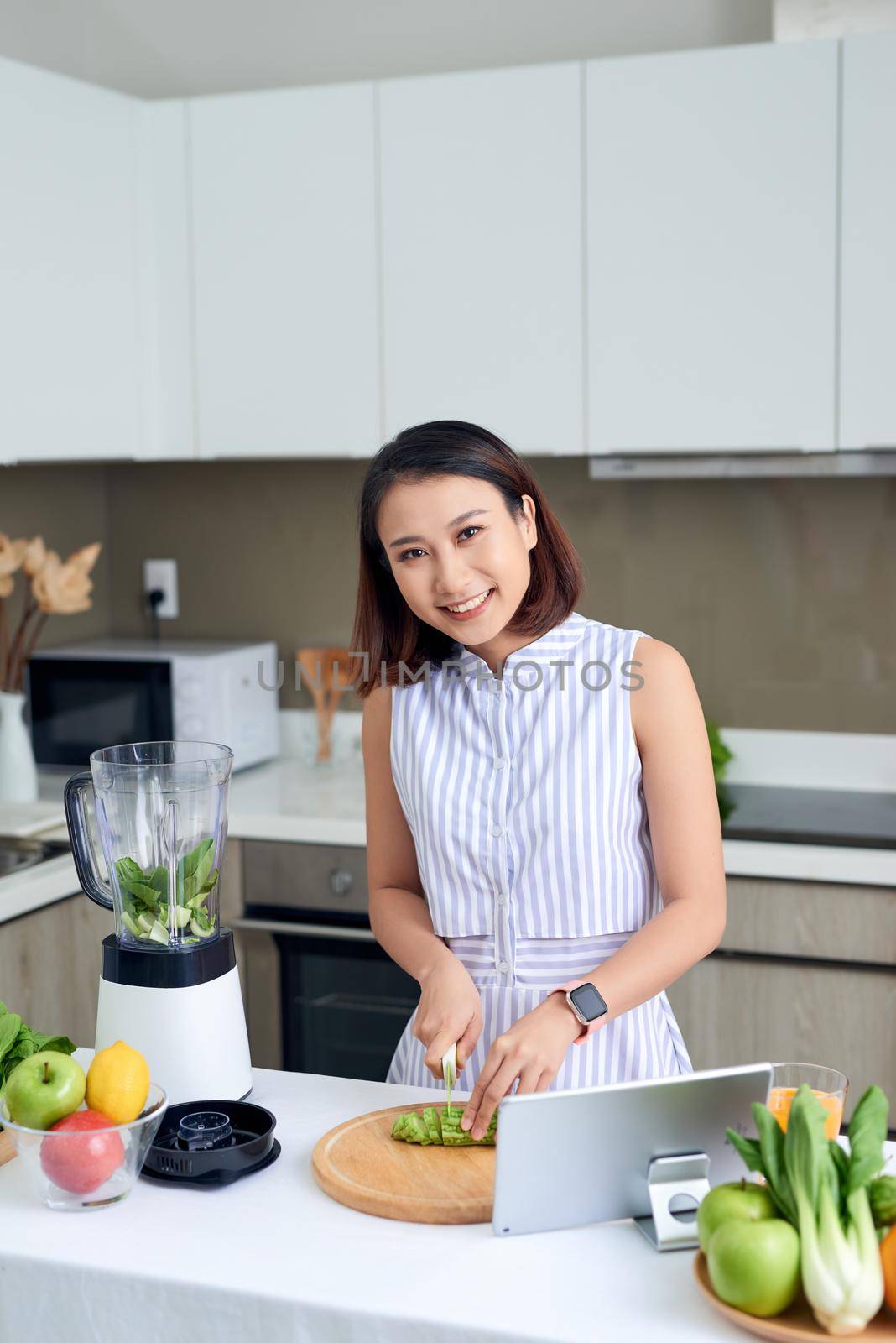 Healthy Asian woman enjoy making green vegetables detox cleanse and green fruit smoothie with blender in kitchen at home. dieting concept.healthy lifestyle