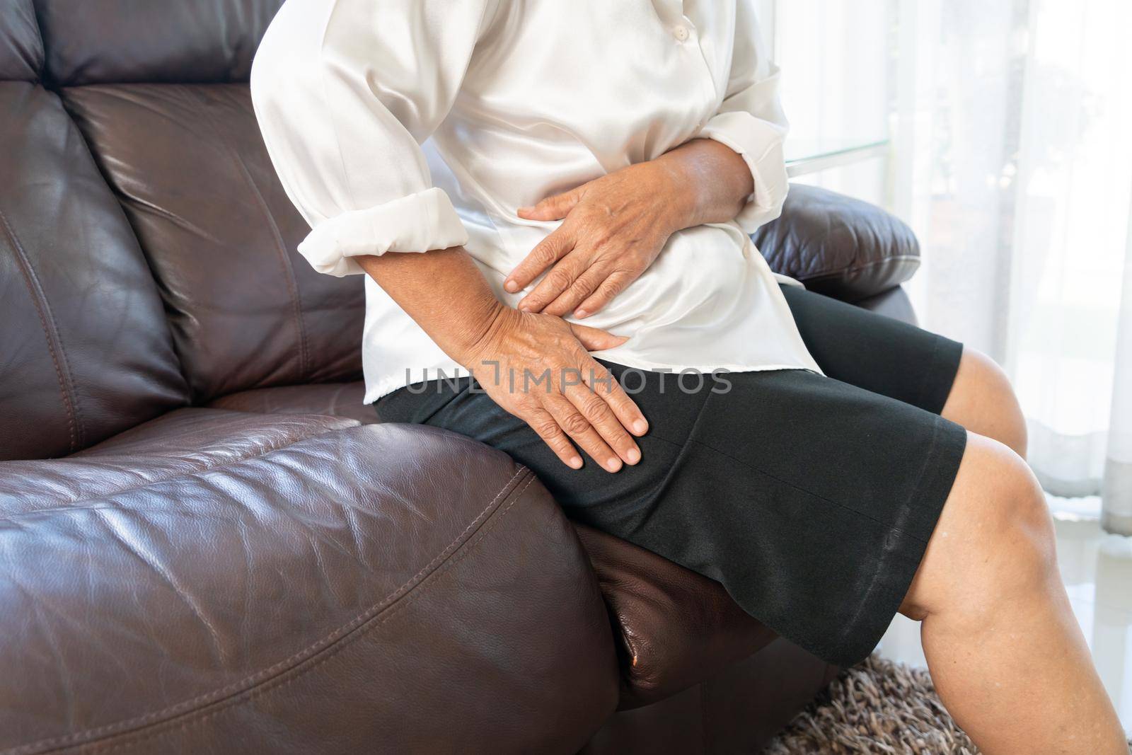 Hip pain of senior woman at home, healthcare problem of senior concept by psodaz