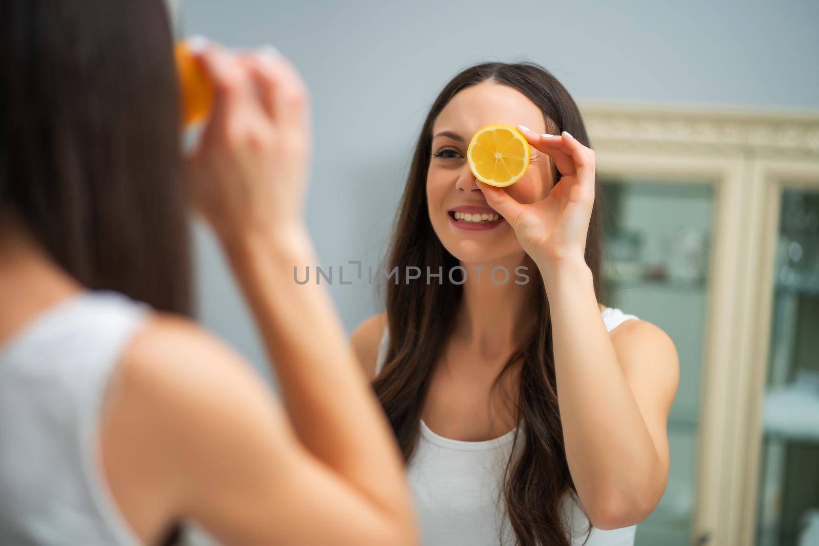 Beautiful young woman is holding lemon and smiling.