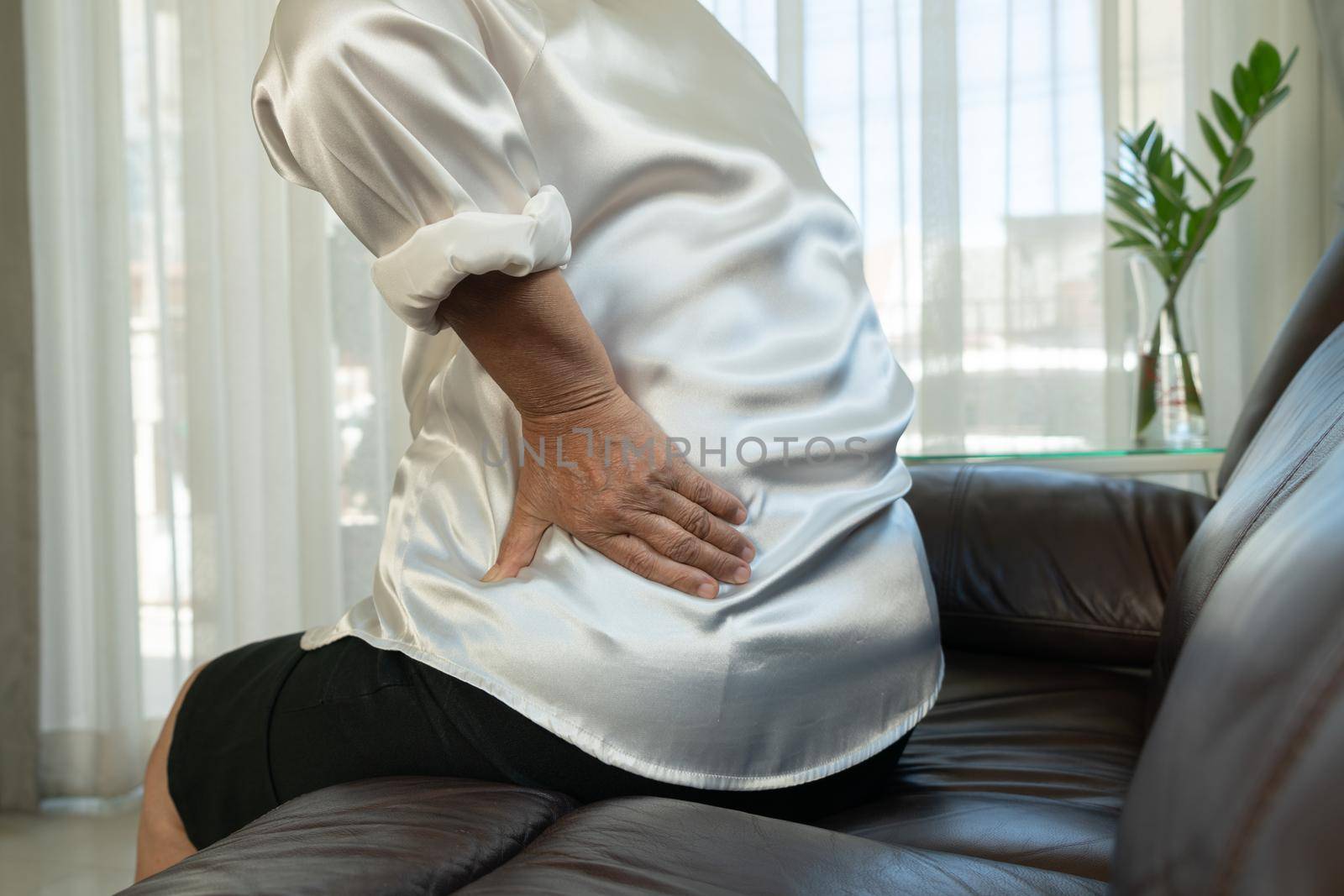 Old woman back pain at home, health problem concept by psodaz