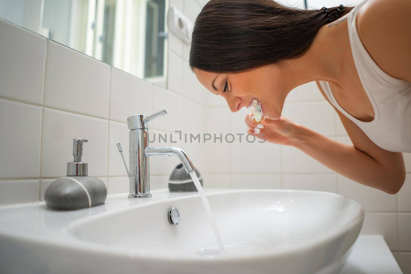 Portrait of young woman who is cleaning her teeth.