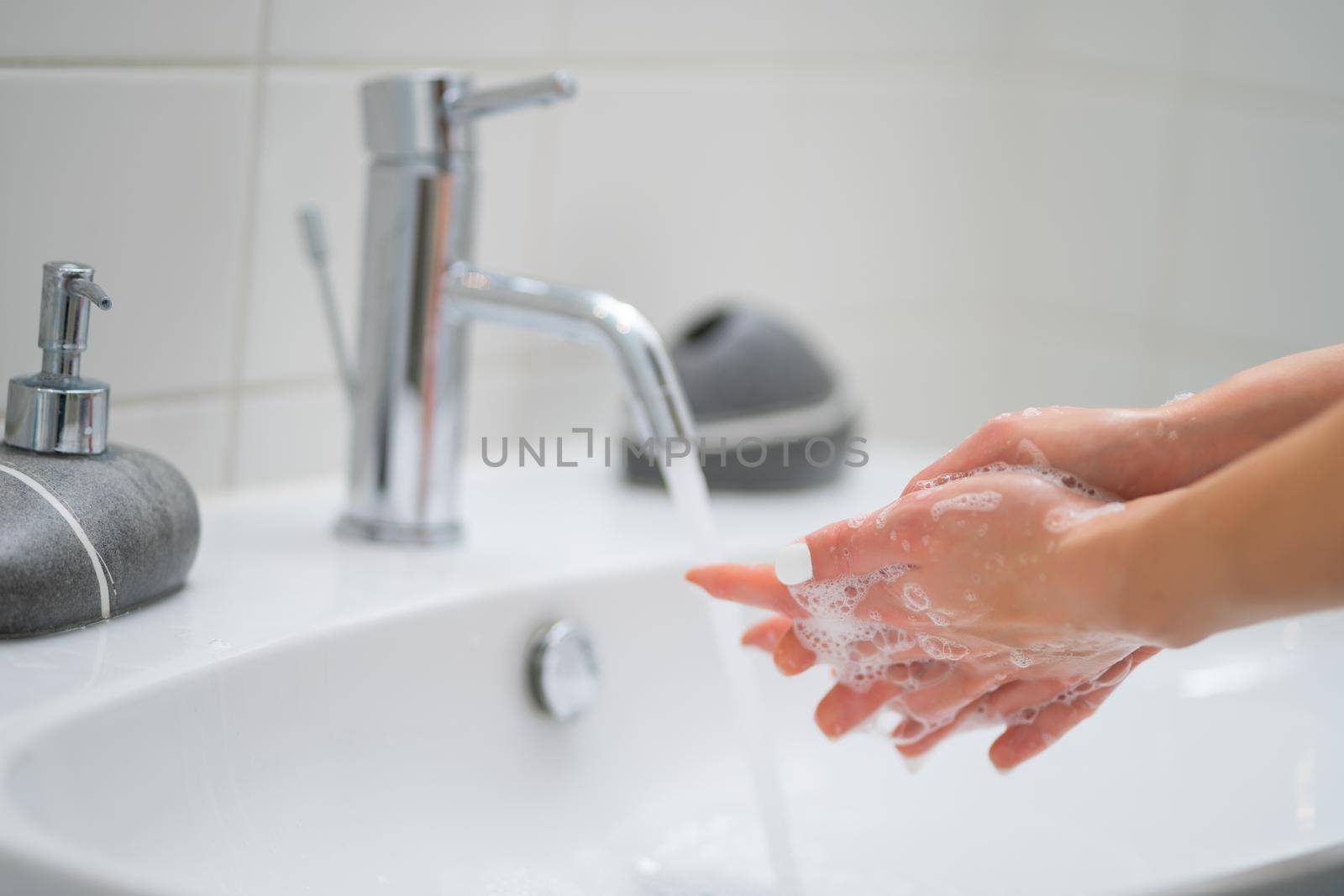 Close-up image of woman washing hands in bathroom.