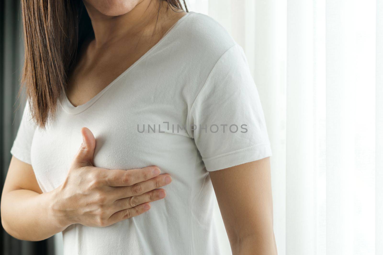 Woman hand checking lumps on her breast for signs of breast cancer. Women healthcare concept. by psodaz