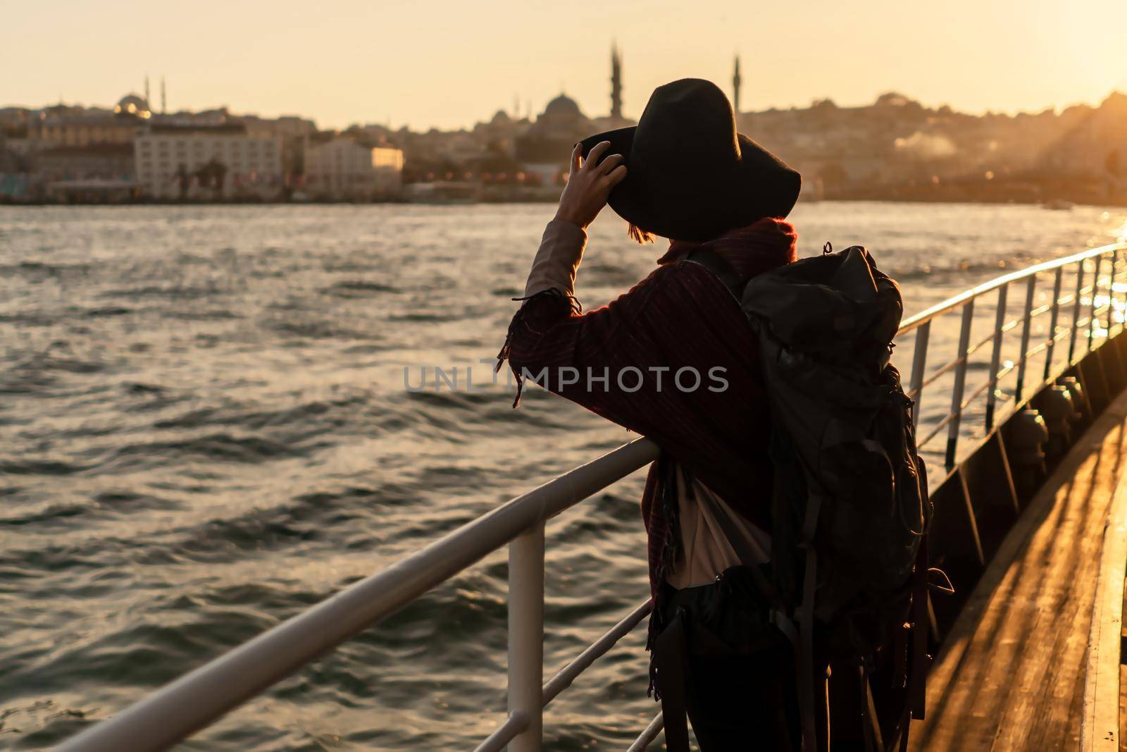 A young girl in a hat and with a backpack looks at the coast of Istanbul from the side of the ferry. The beginning of a great adventure in the Arab countries.