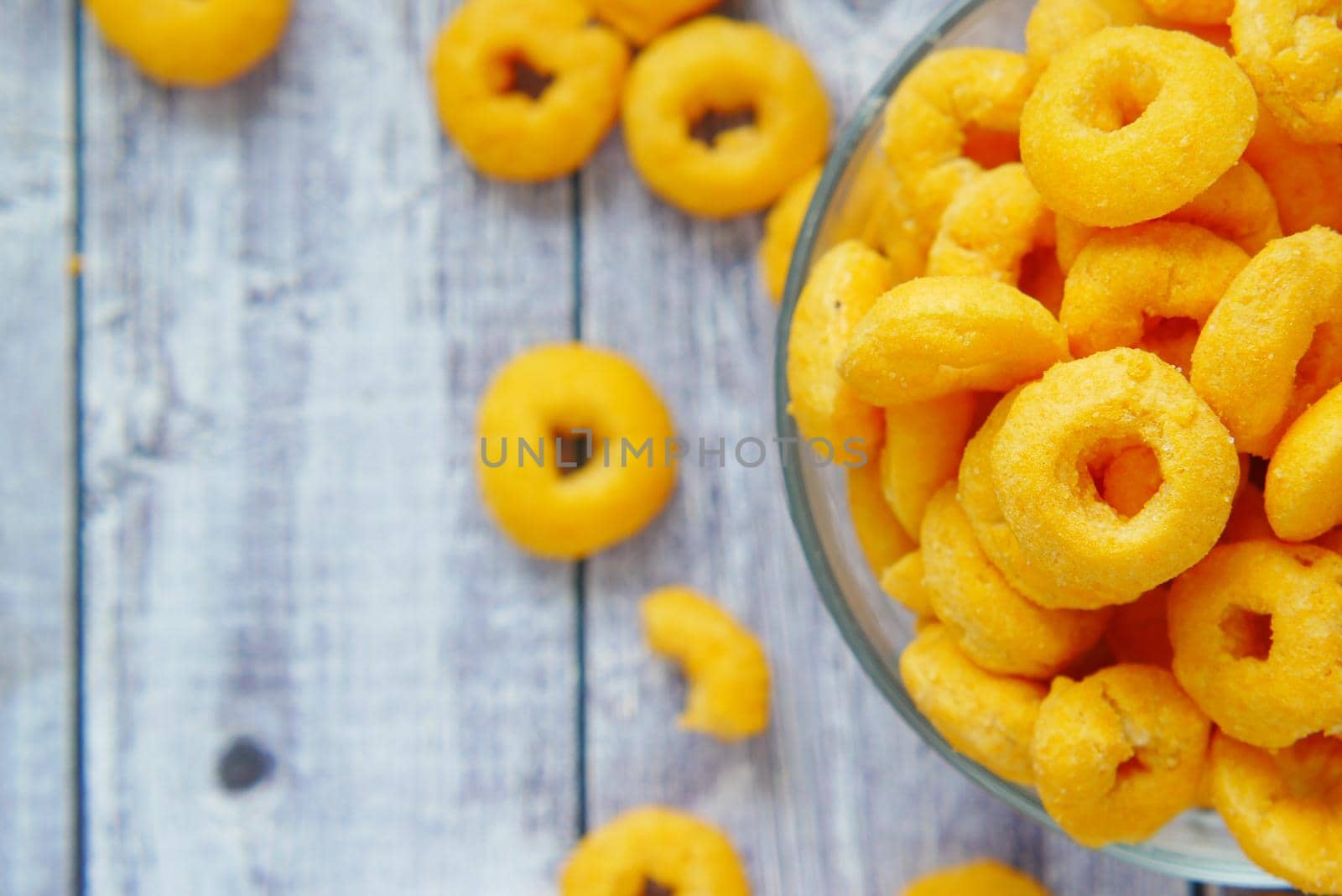 puffed corn rings chips in black bowl on white background,