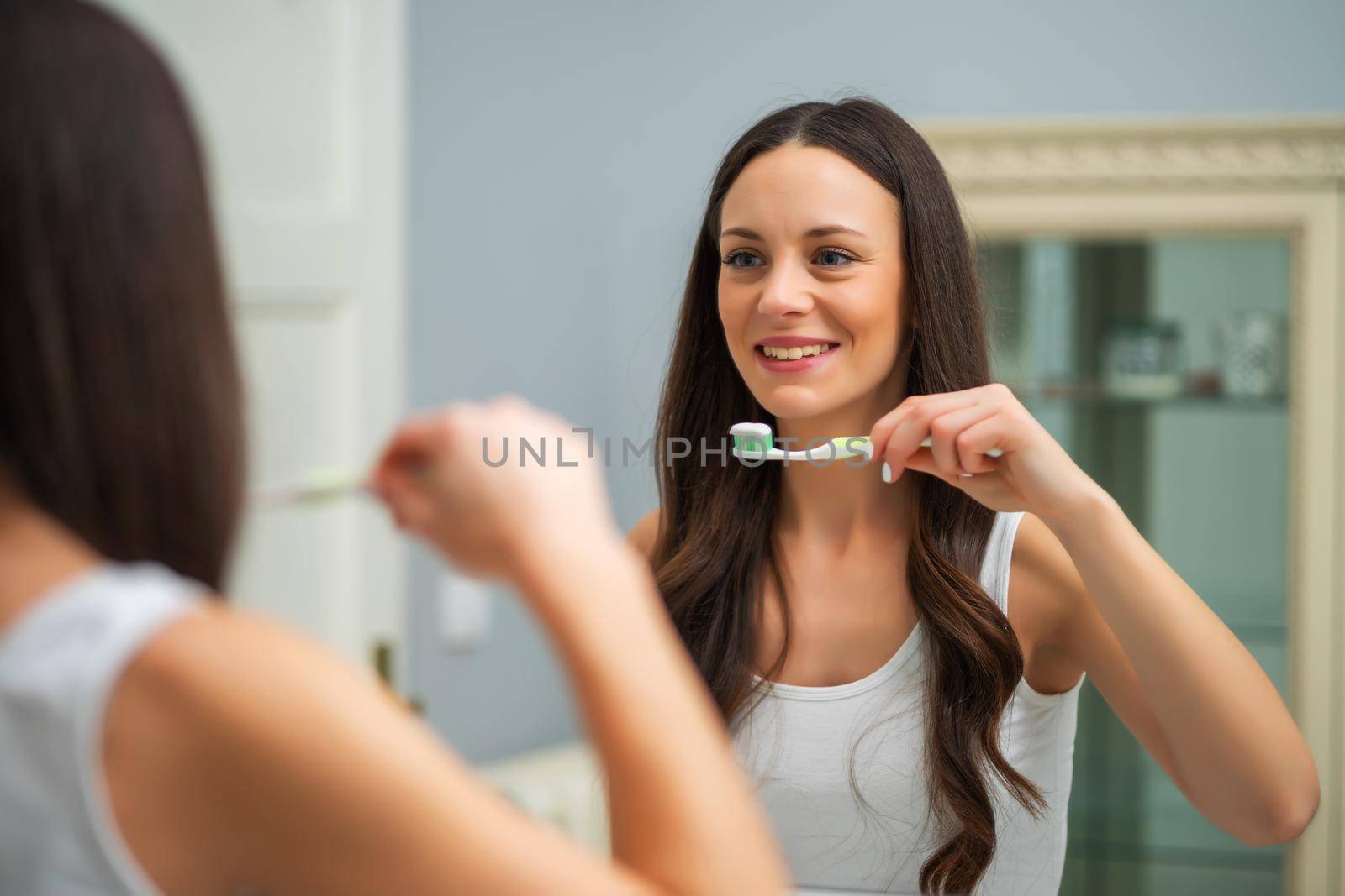 Young woman is brushing her teeth in bathroom.