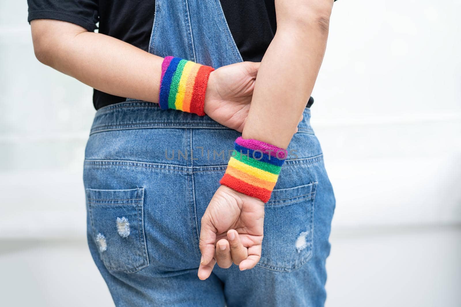 Asian lady wearing rainbow flag wristbands, symbol of LGBT pride month celebrate annual in June social of gay, lesbian, bisexual, transgender, human rights. by pamai