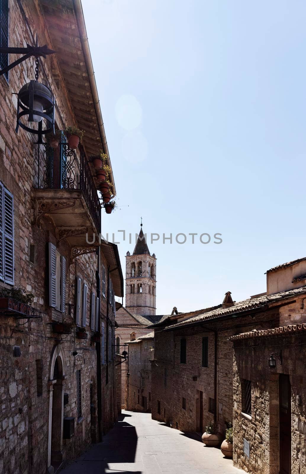 Beautiful alley in Assisi, Italy , old medieval town ,in the background bell tower of Santa Chiara church