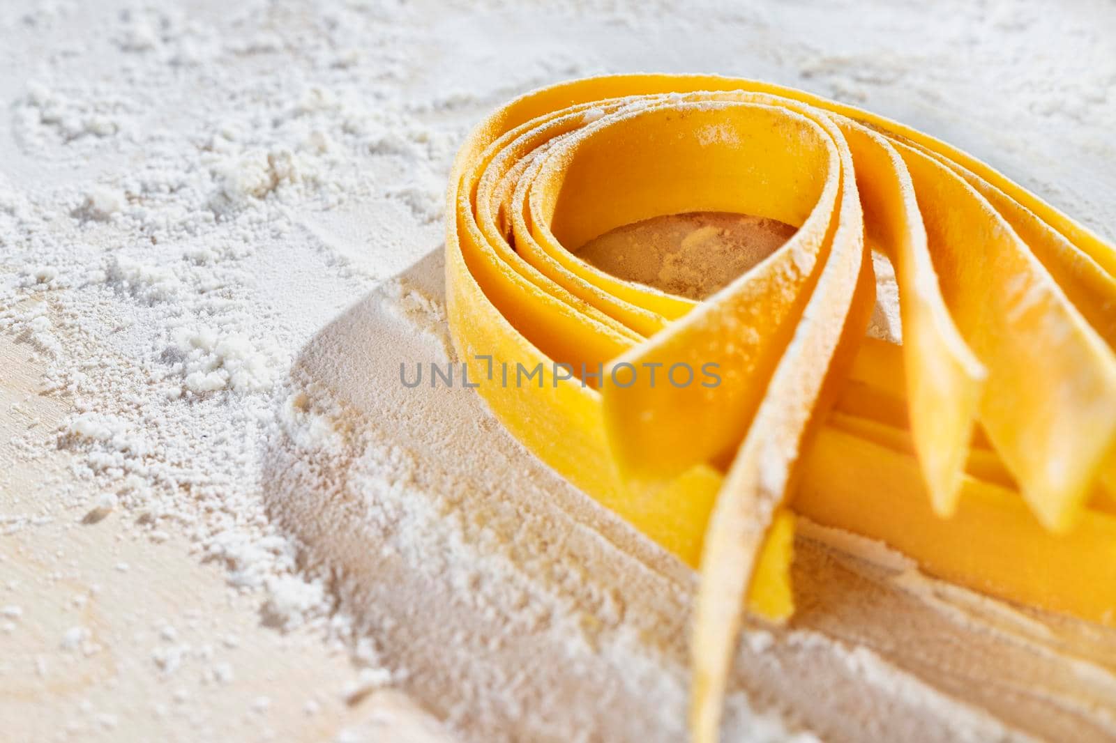 Large flat egg  pasta pappardelle with flour on wooden background , uncooked pasta