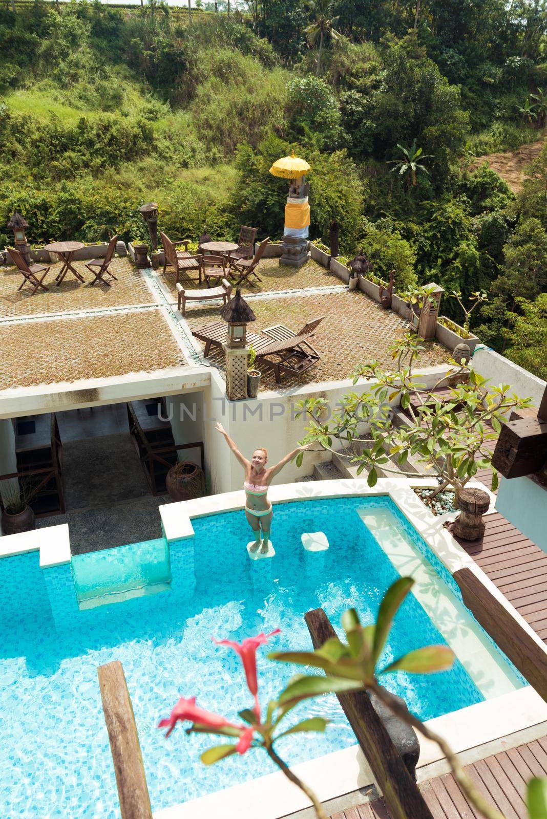 Young woman wearing swimsuit relaxing near swimming pool at exotic location