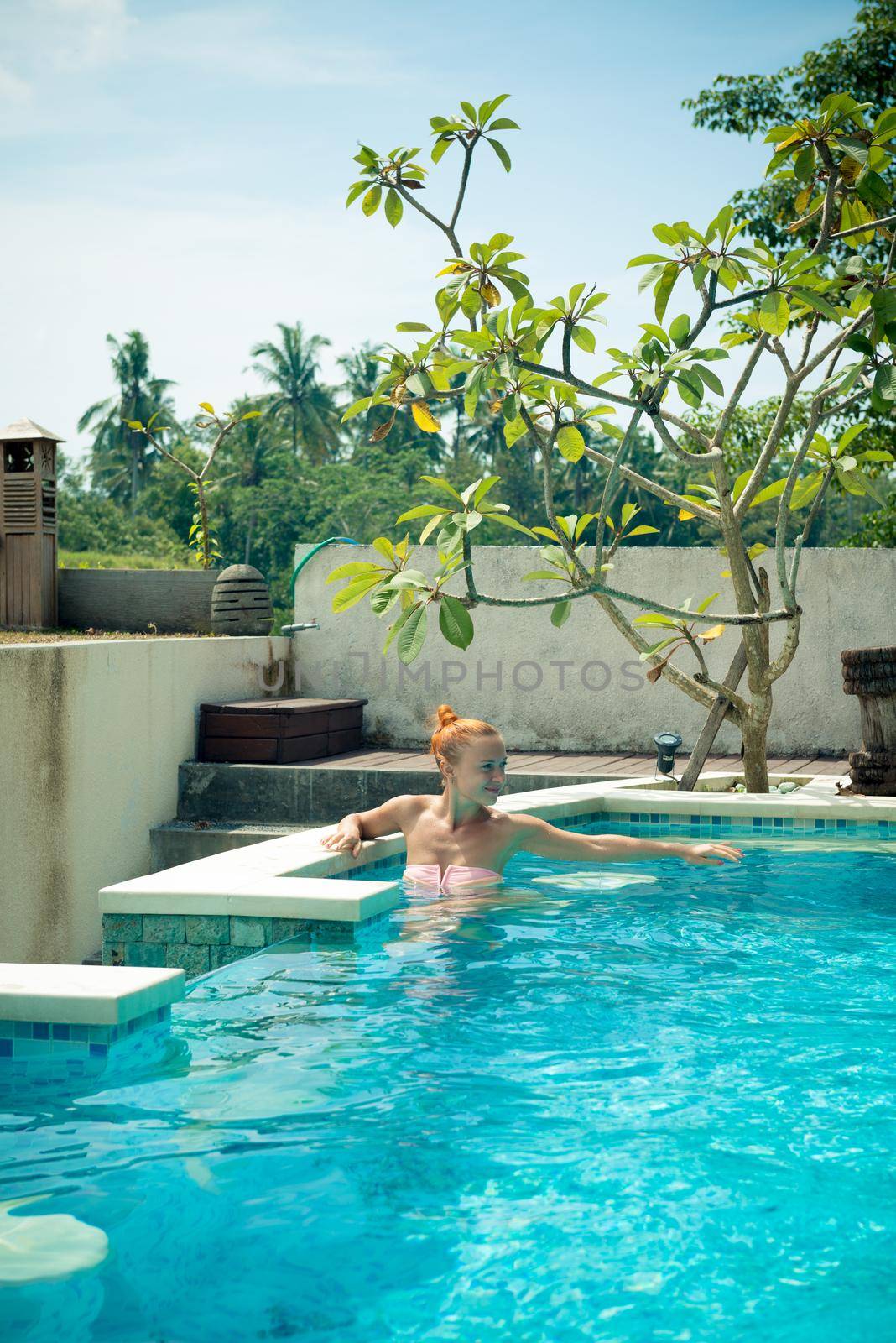 Young woman wearing swimsuit relaxing near swimming pool at exotic location