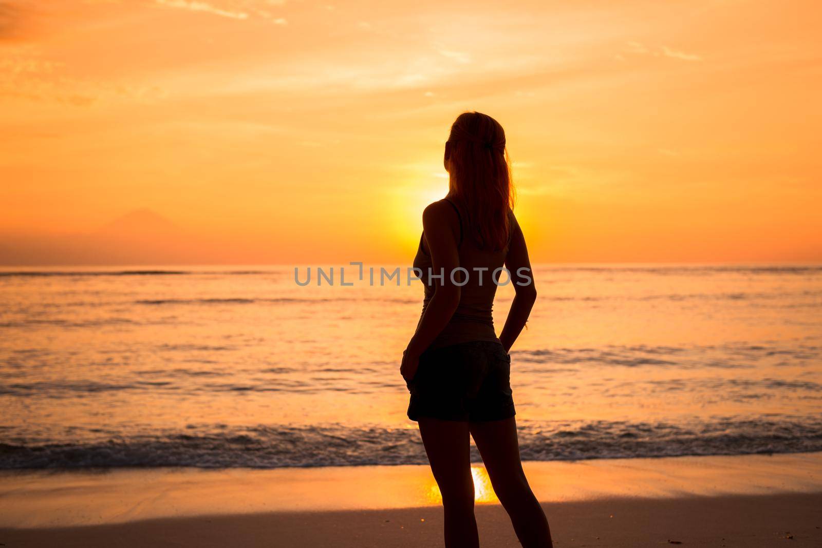 Young woman watching as sun sets over Pacific Ocean