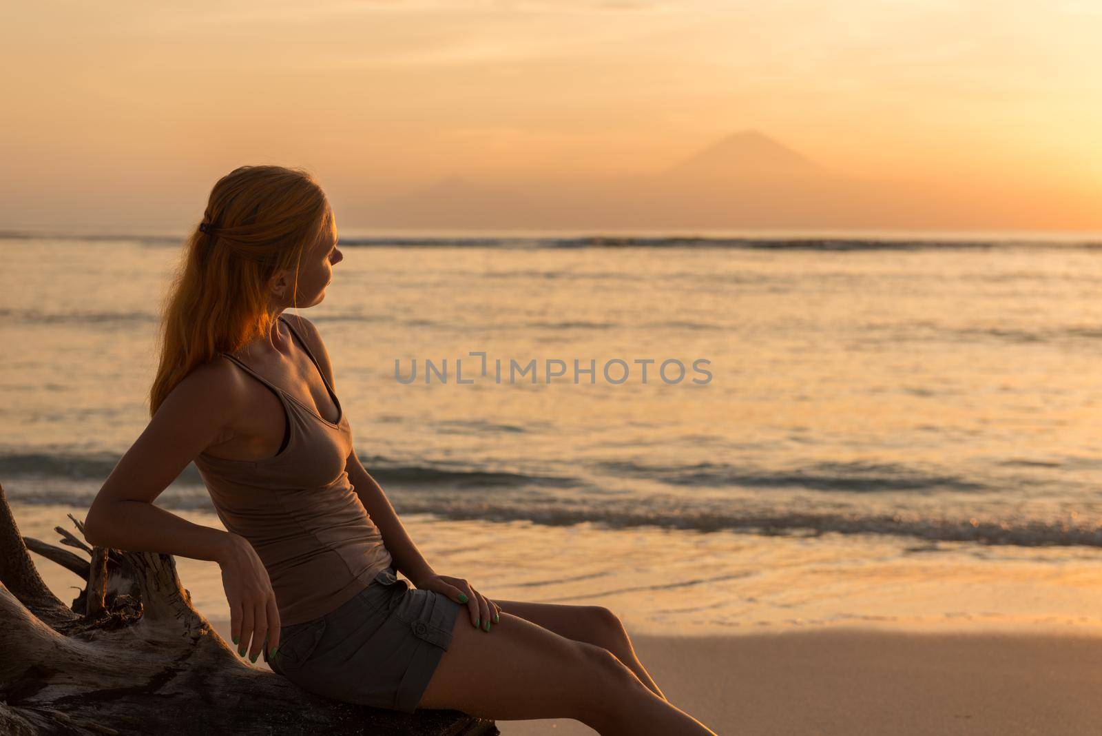 Young woman watching as sun sets over Pacific Ocean