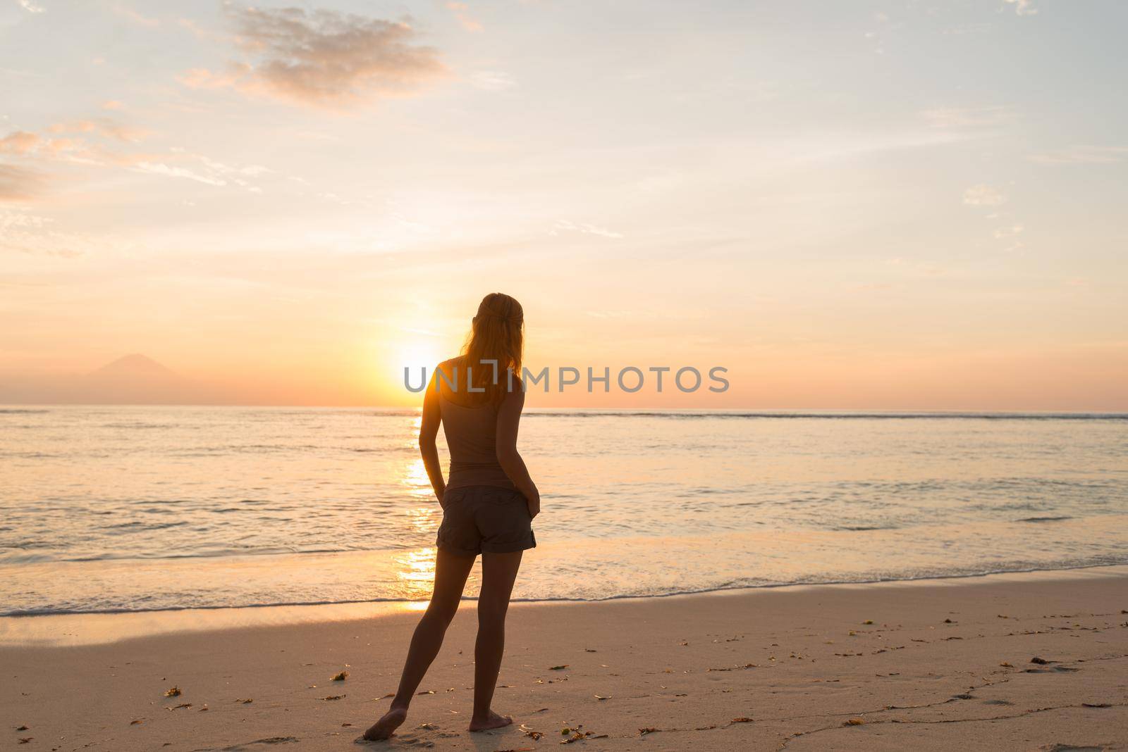 Young woman watching as sun sets over Pacific Ocean