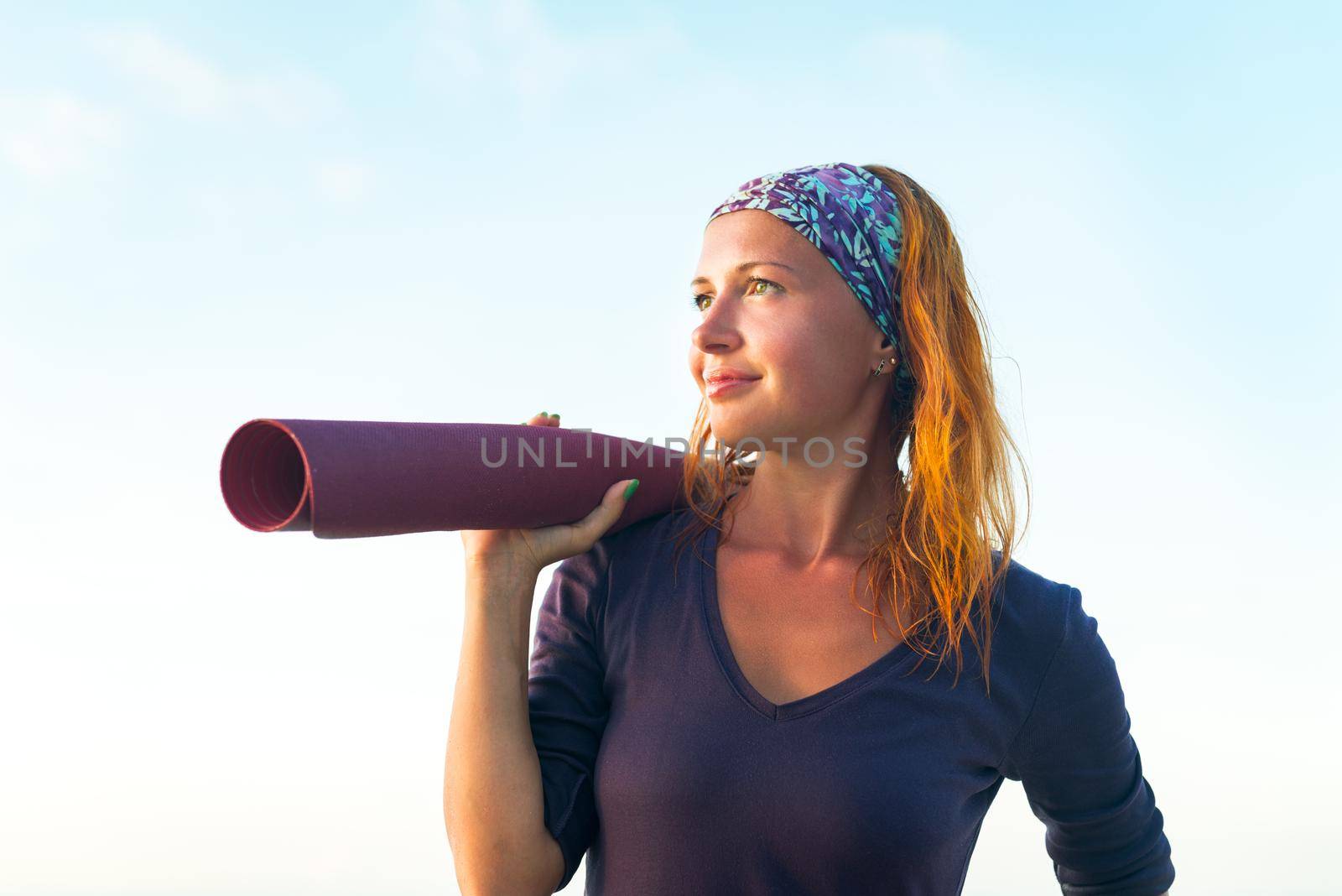Young woman with long red hair and yoga mat