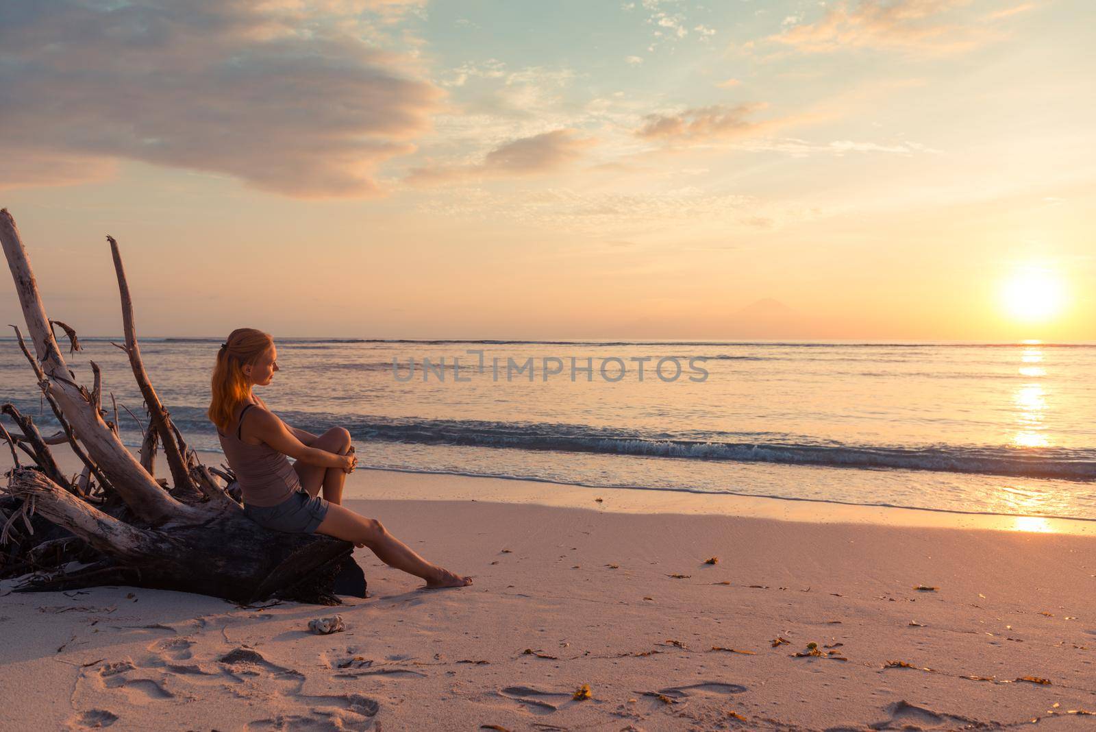 Young woman watching as sun sets over Pacific Ocean