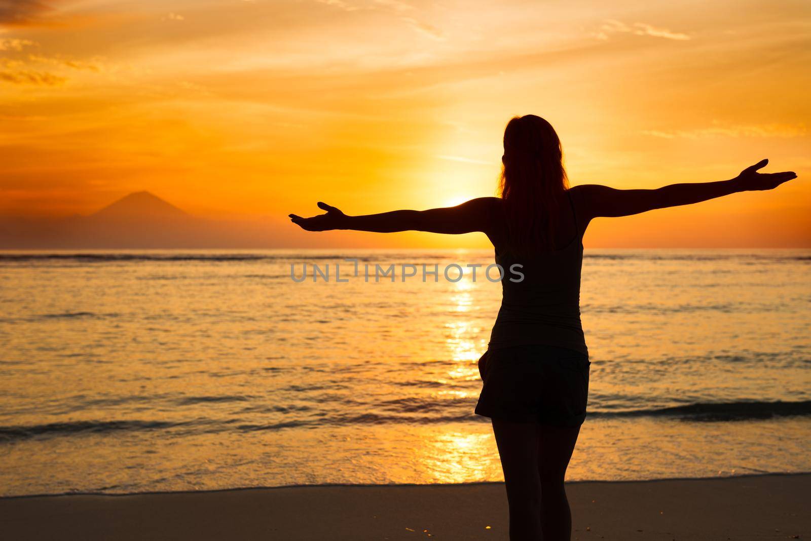 Young woman watching as sun sets over Pacific Ocean