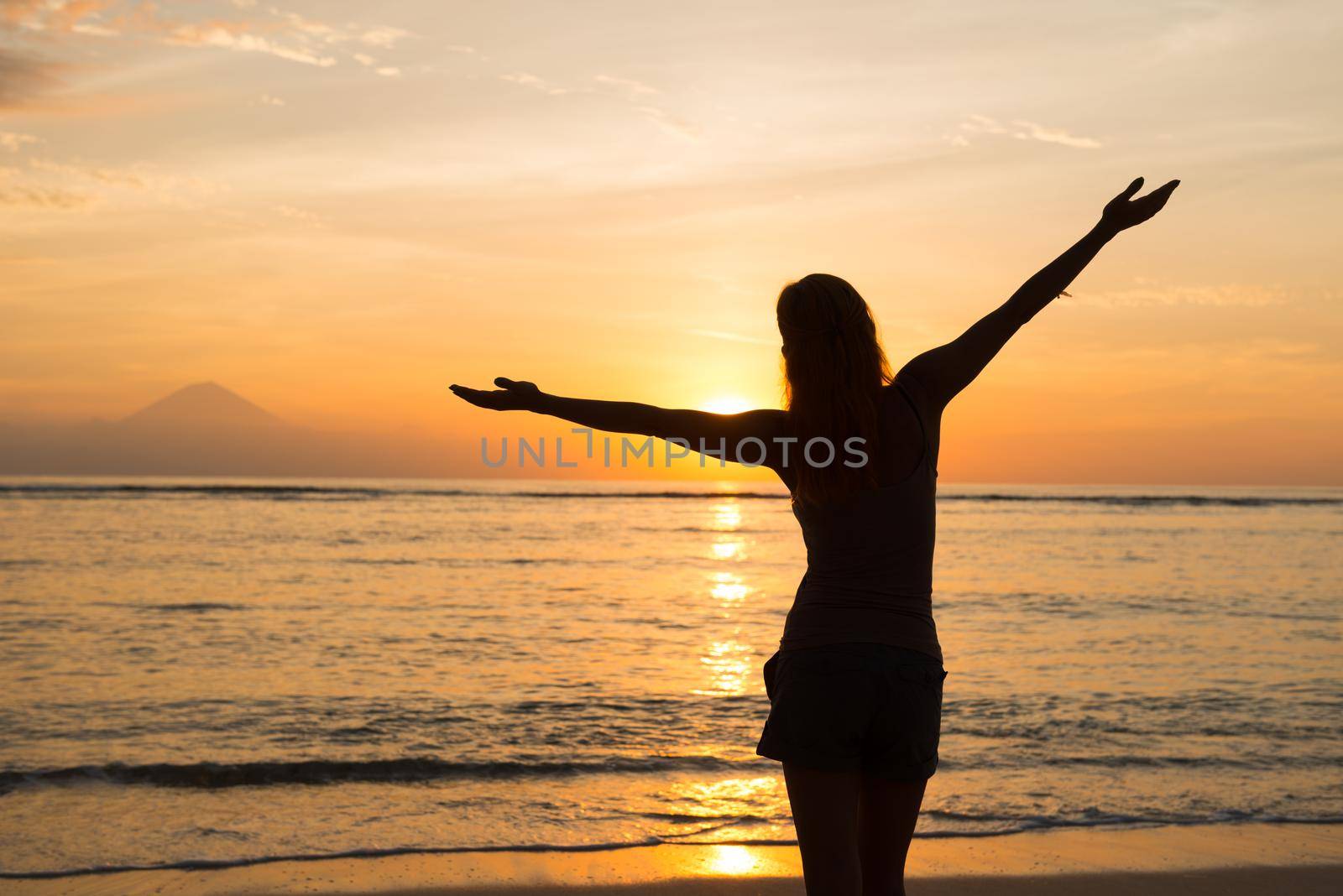 Young woman watching as sun sets over Pacific Ocean