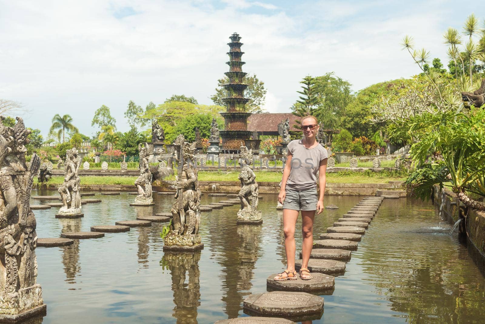 Happy tourist at Tirtagangga water palace with fountains and ponds on Bali, Indonesia