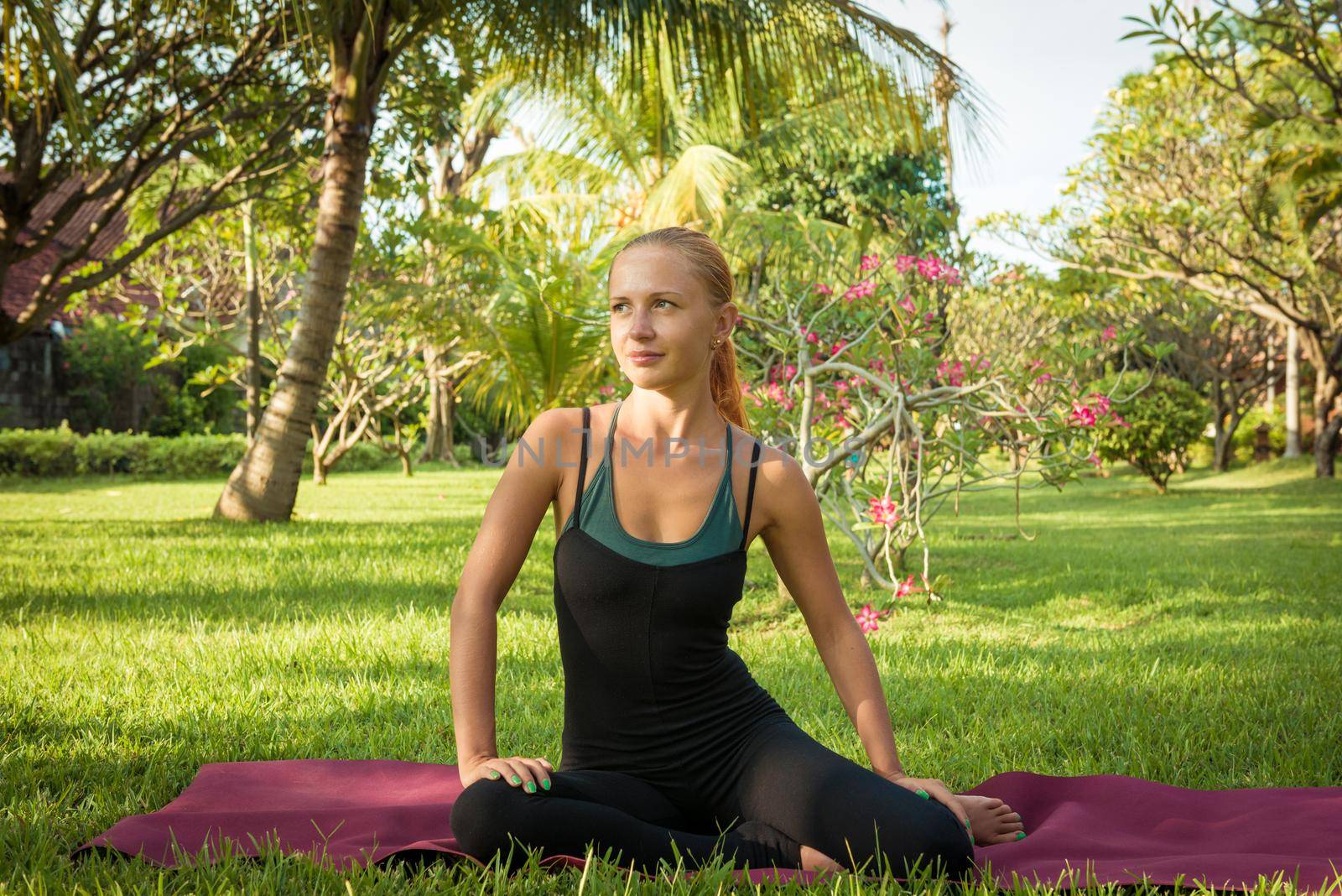 Young woman doing yoga exercises in the lush tropical garden