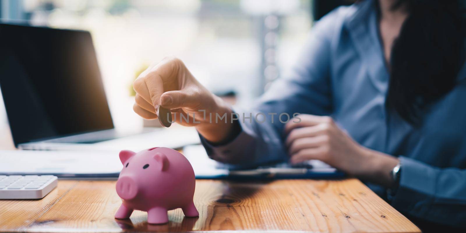 Young woman putting a coin inside piggy bank as savings for investment. wealth and financial concept. by itchaznong