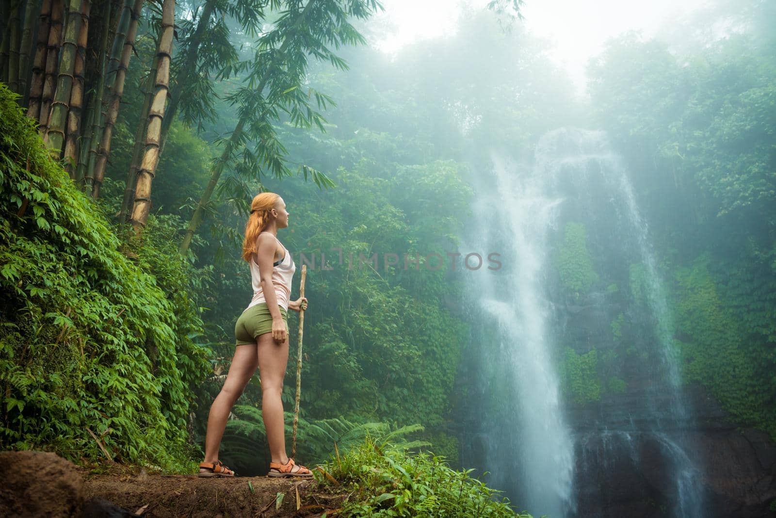 Female adventurer looking at waterfall in Bali jungle