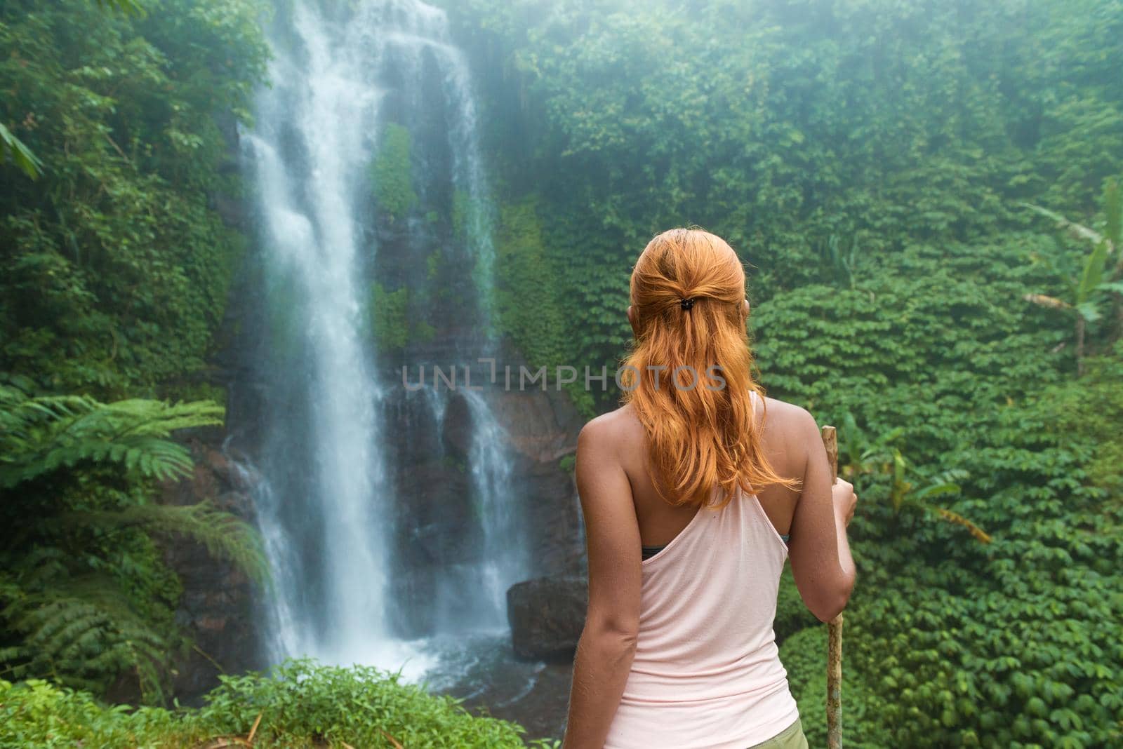 Female adventurer looking at waterfall in Bali jungle
