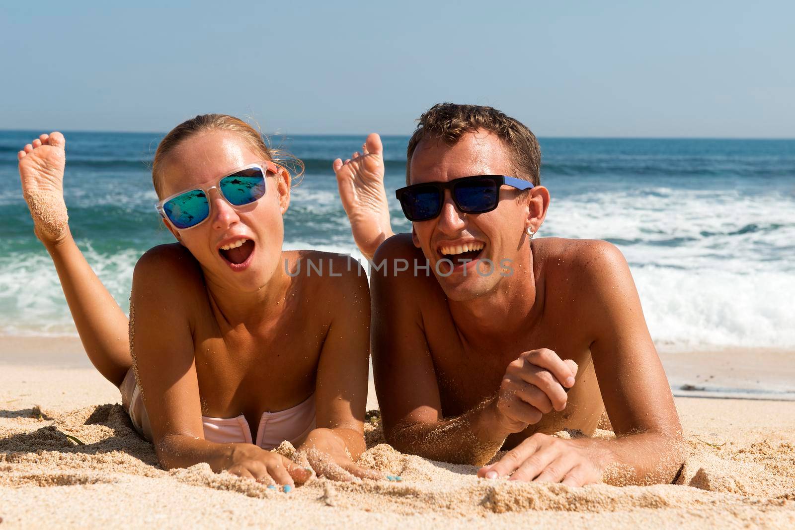 Happy couple having fun on the beach. Summer Vacation. Laughing Family enjoying Nature over Sea Background. Attractive Man and Woman at the Beach
