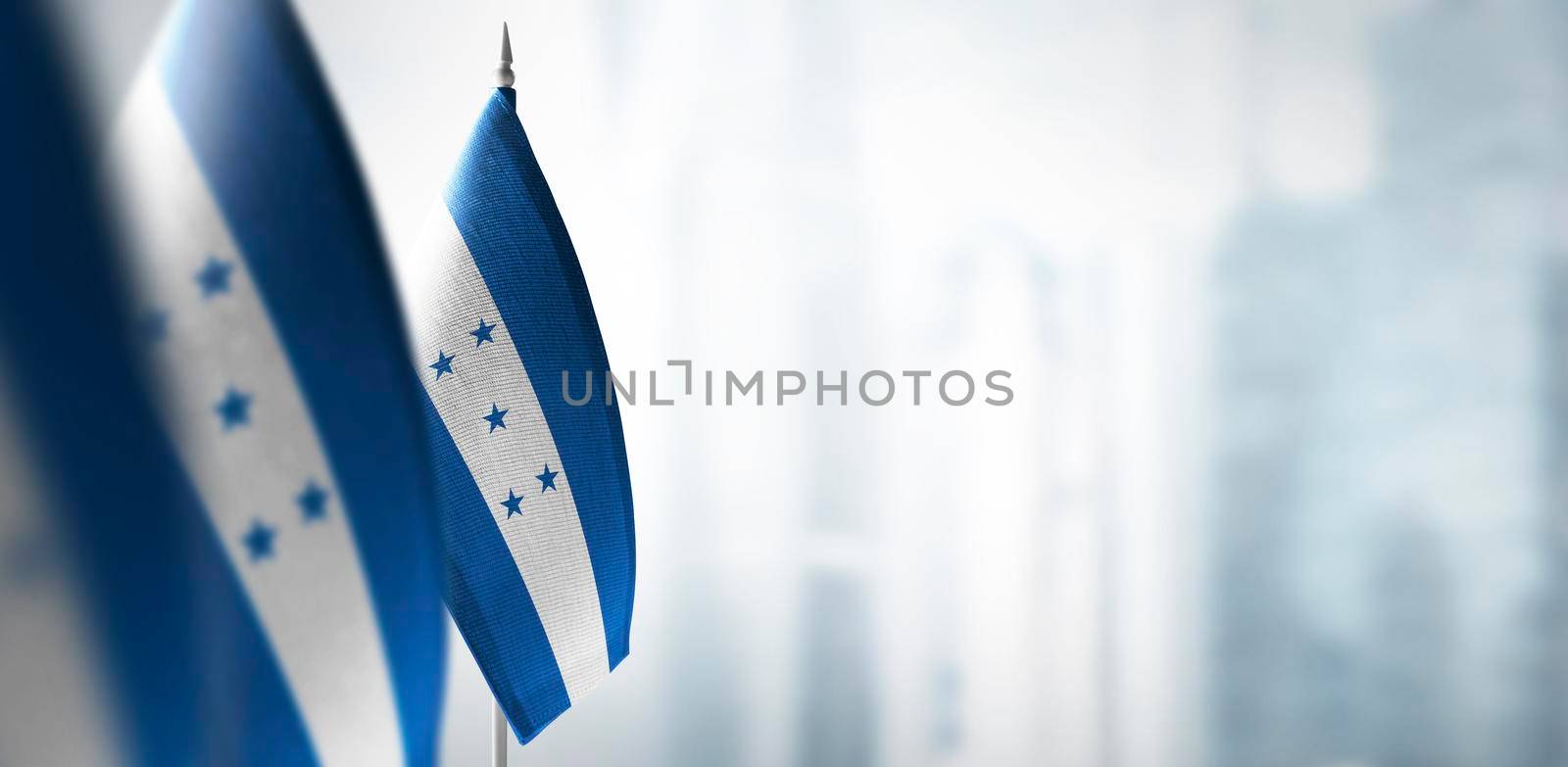 Small flags of Honduras on a blurry background of the city.