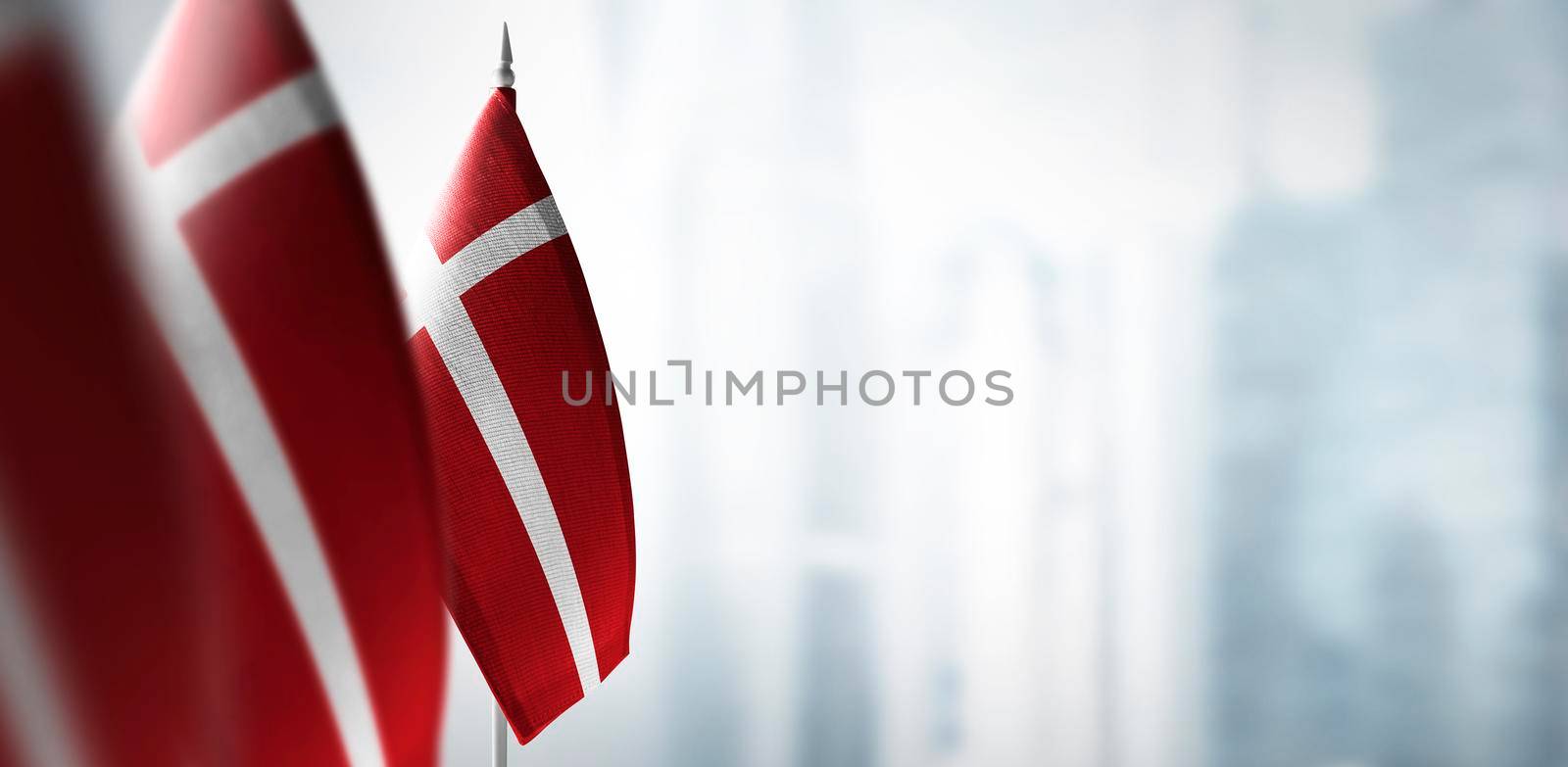 Small flags of Denmark on a blurry background of the city by butenkow