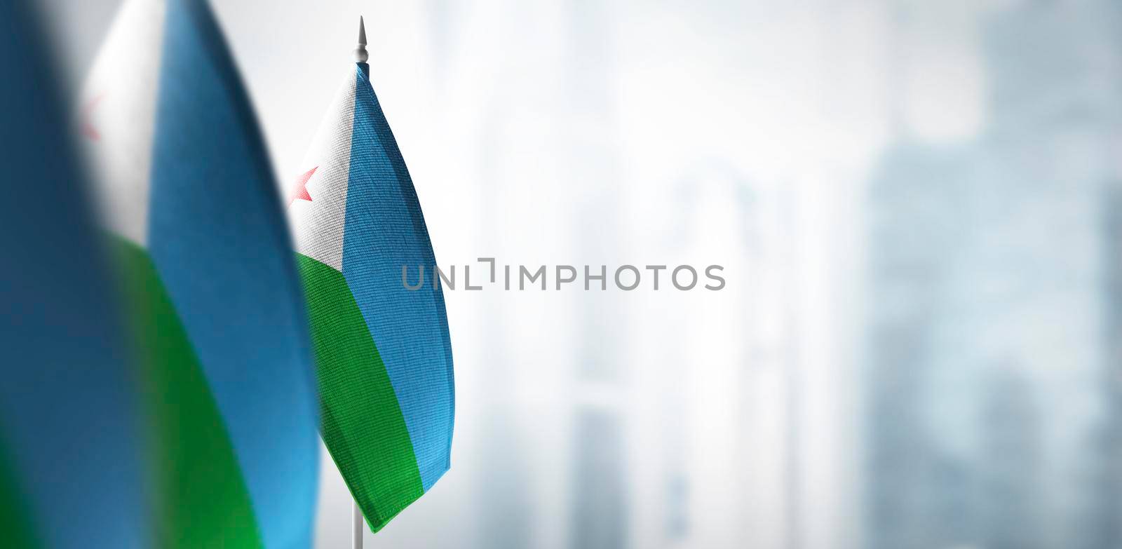 Small flags of Djibouti on a blurry background of the city.