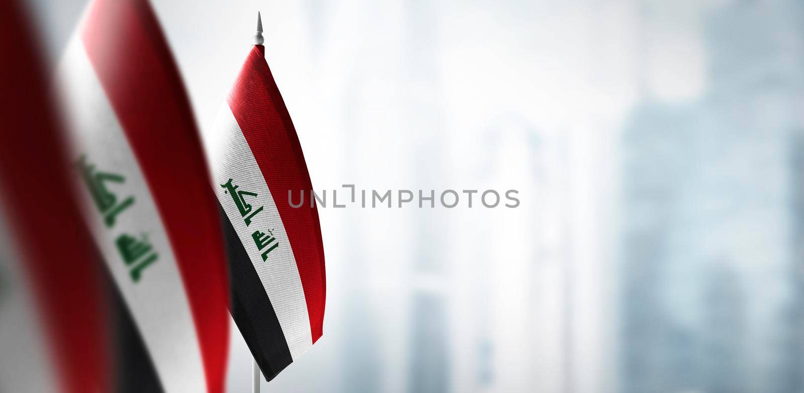 Small flags of Iraq on a blurry background of the city.