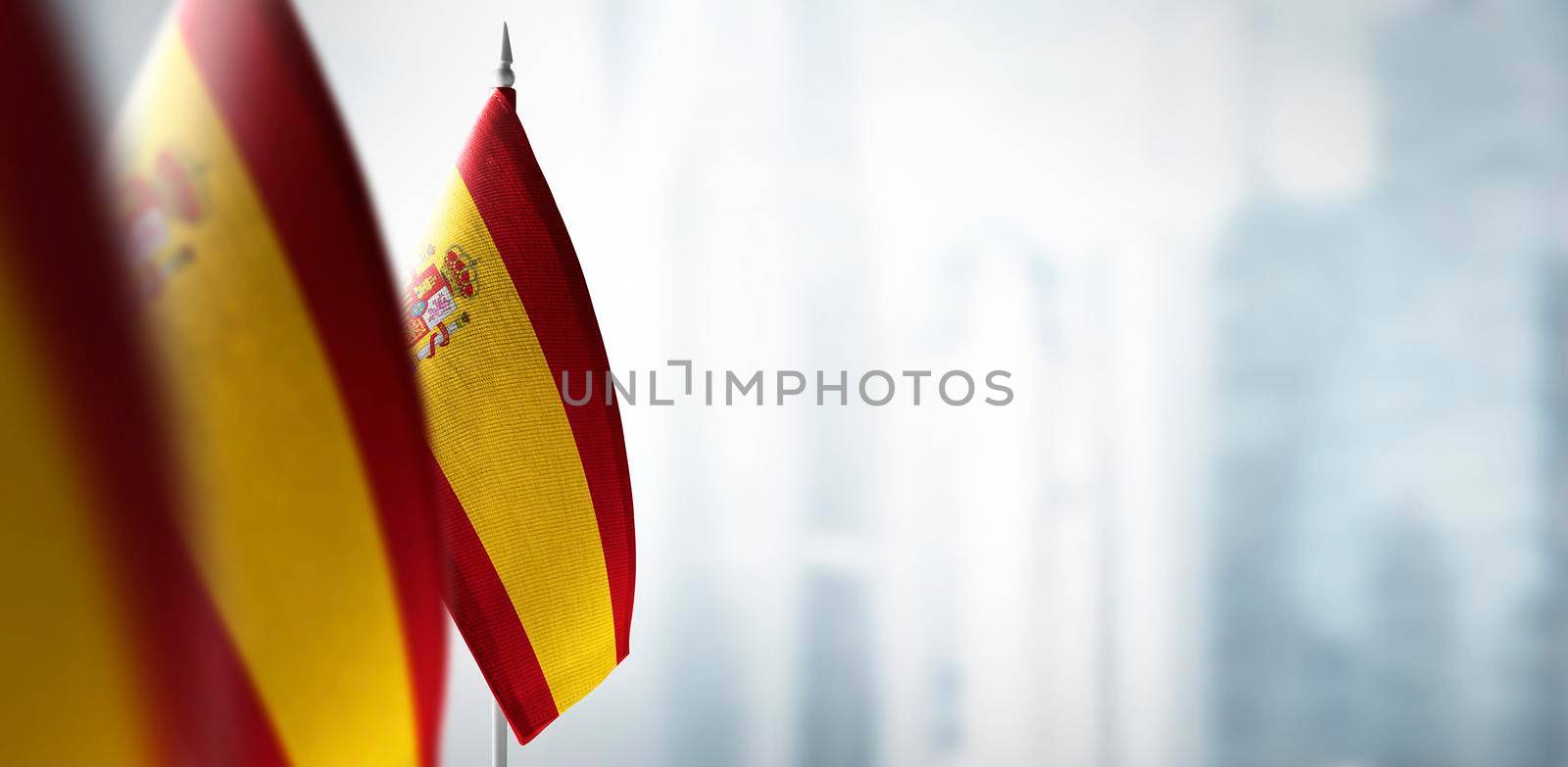 Small flags of Spain on a blurry background of the city by butenkow