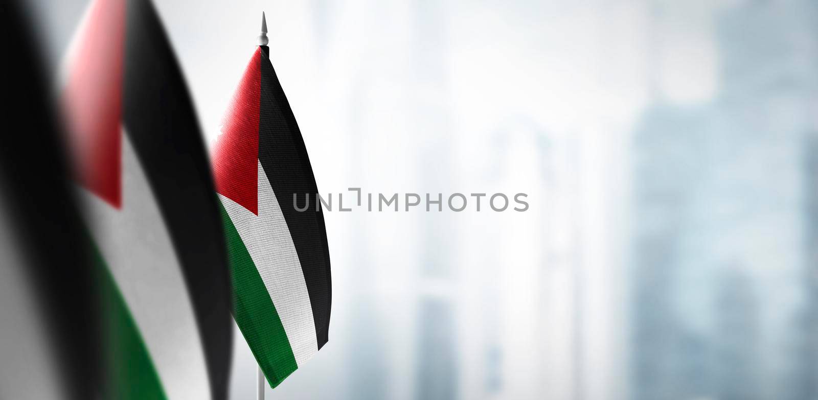 Small flags of Jordan on a blurry background of the city.