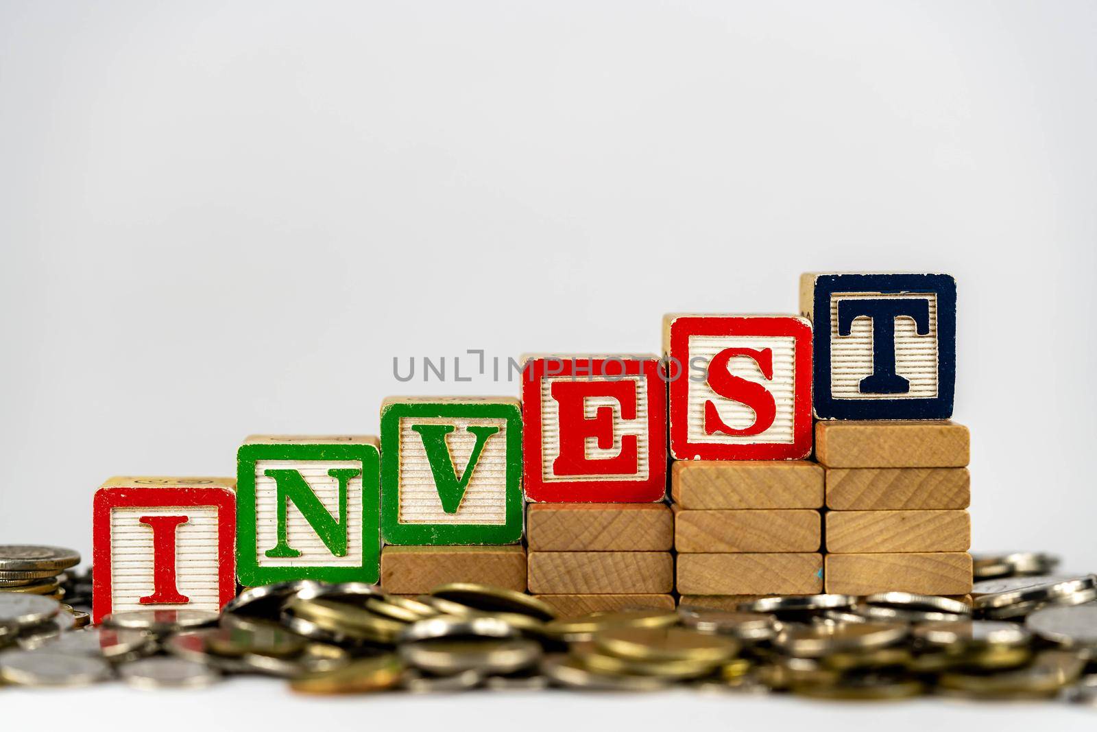 Investment concept with wooden blocks and coins. Invest letters on wooden blocks sorrounded with money