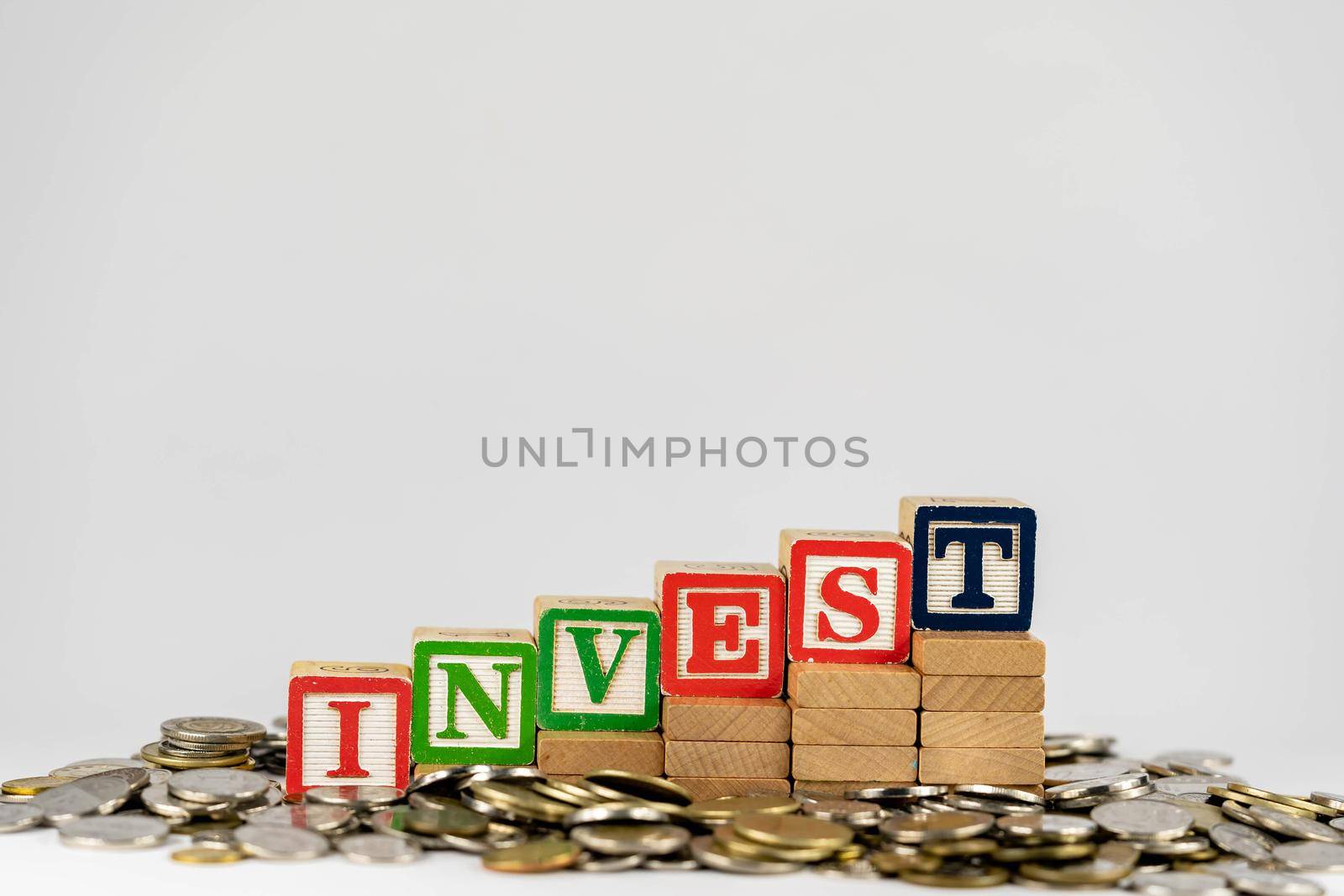 Investment concept with wooden blocks and coins. Invest letters on wooden blocks sorrounded with money by billroque