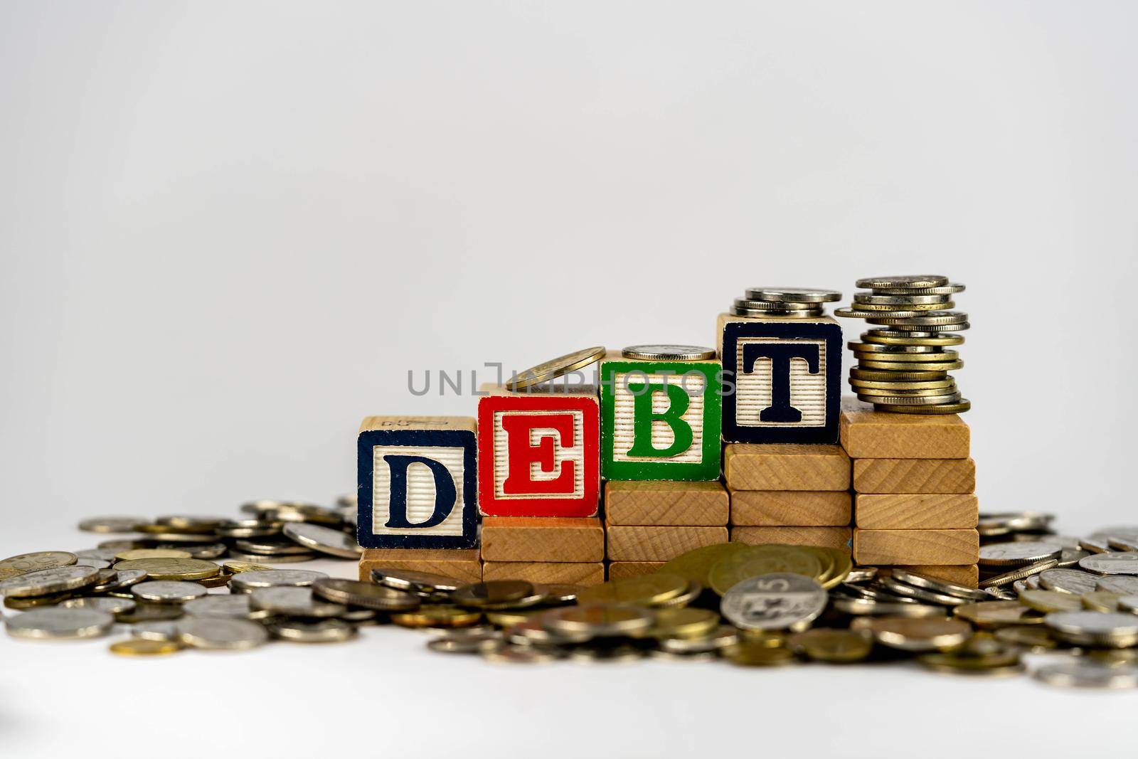 Debt concept with wooden blocks and coins. Debt letters on wooden blocks sorrounded with money