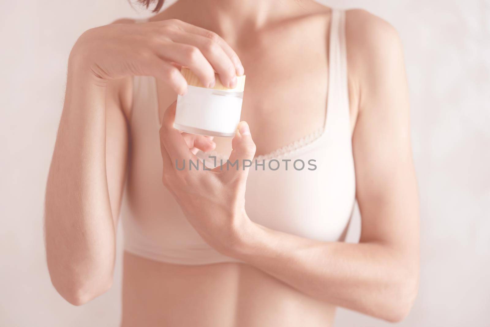 Young female hands hold a jar of moisturizing cream to maintain health, softness of the skin, the woman takes care of her health and beauty.