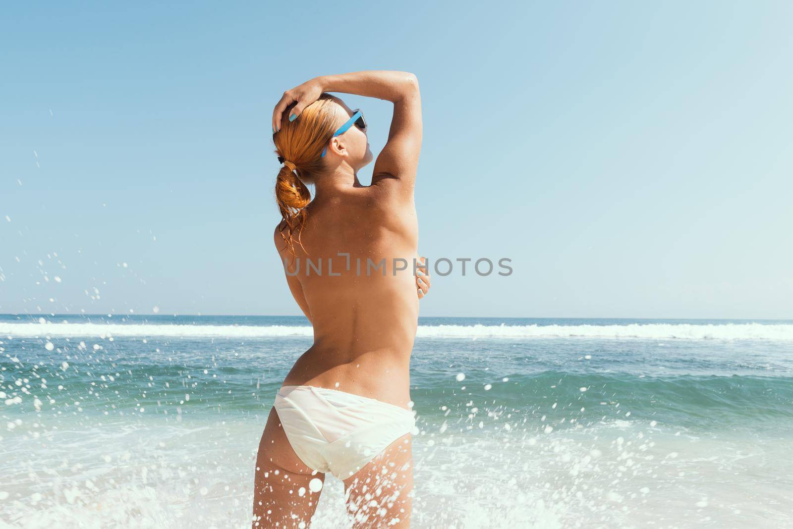 Beautiful sexy young woman topless at the ocean beach
