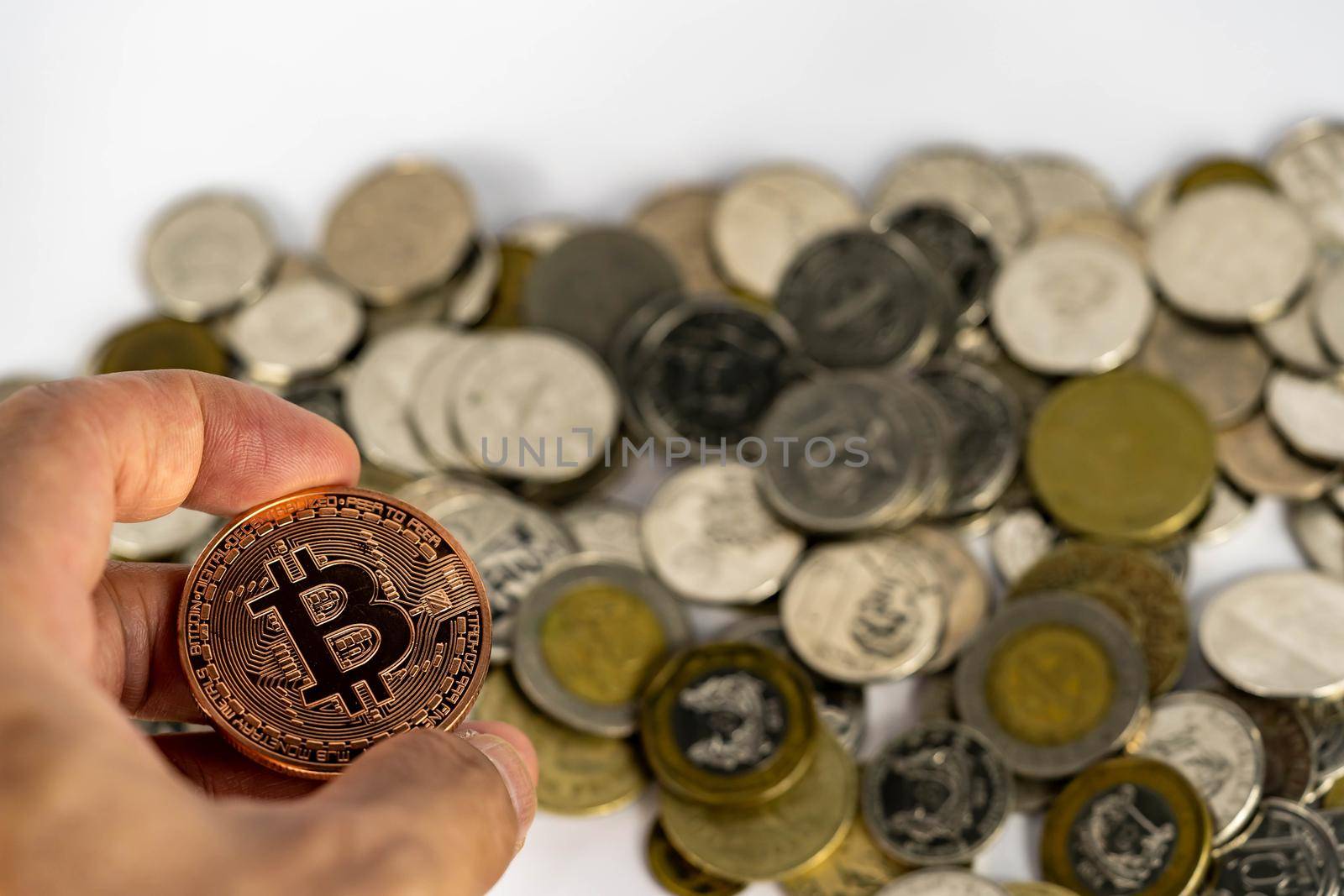 Bitcoin investment concept. Hand holding a bitcoin with blurry coins background by billroque