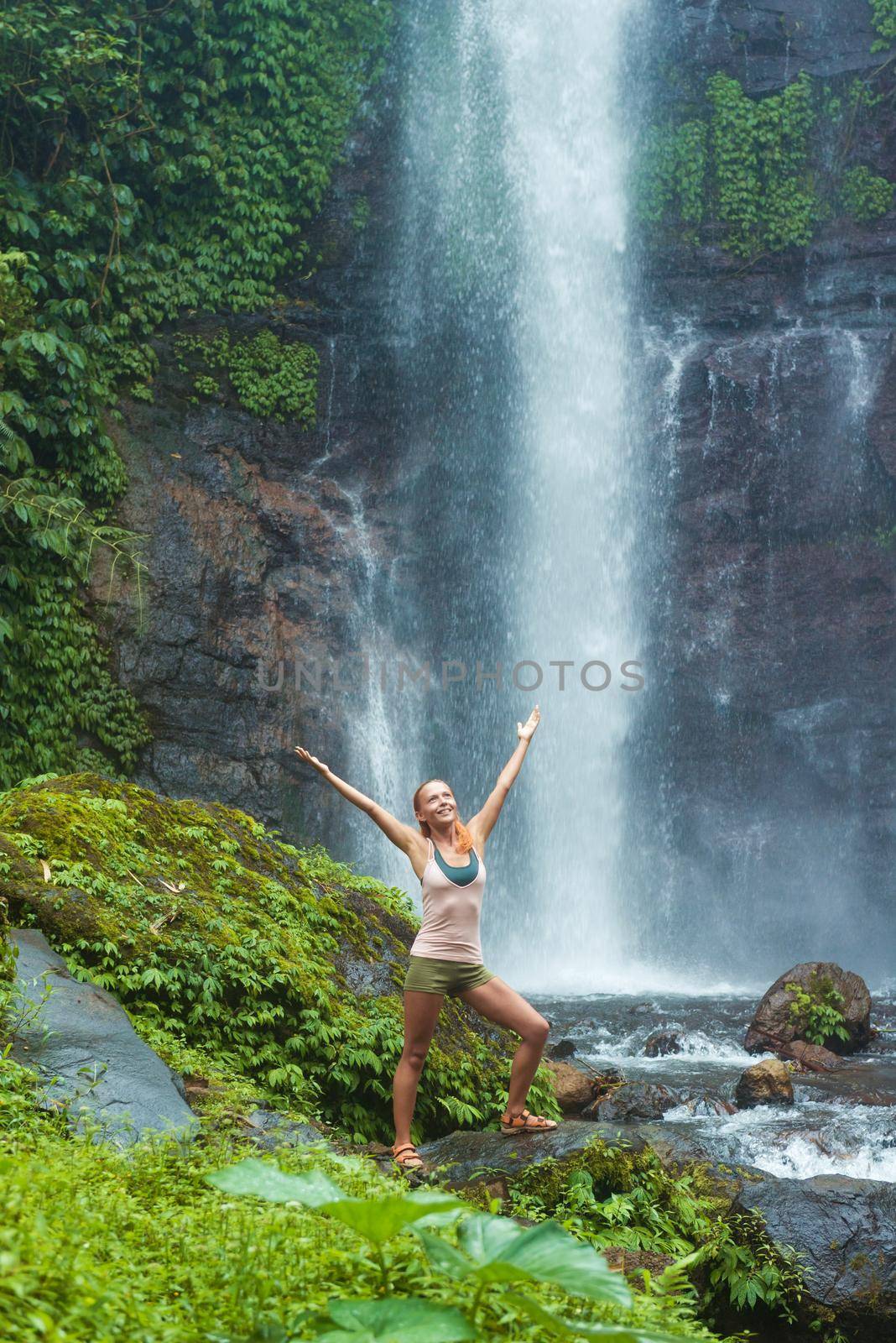 Young woman practicing yoga with waterfall in the background