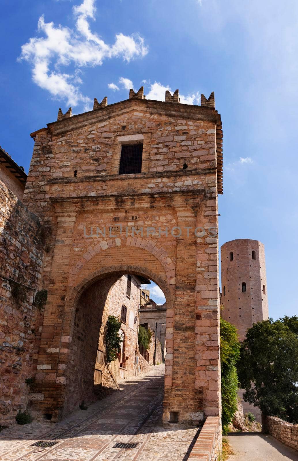 Venus gate in Spello with one Properzio tower in the background , beautiful old medieval walled town