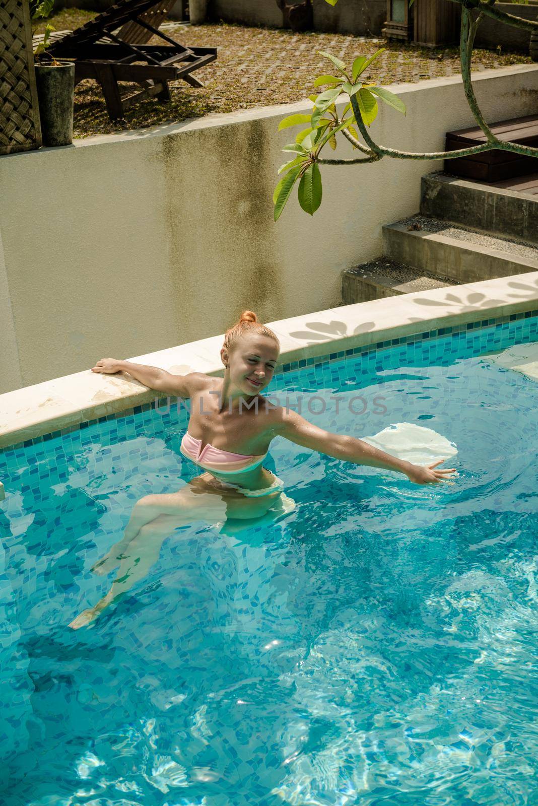 Young woman wearing swimsuit relaxing near swimming pool at exotic location