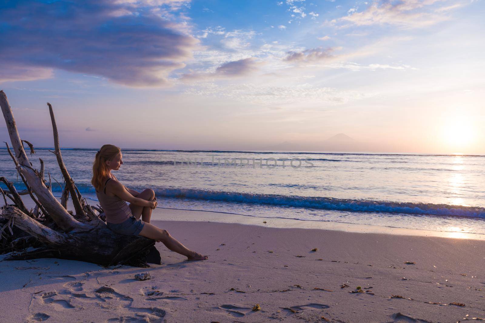 Young woman watching as sun sets over Pacific Ocean