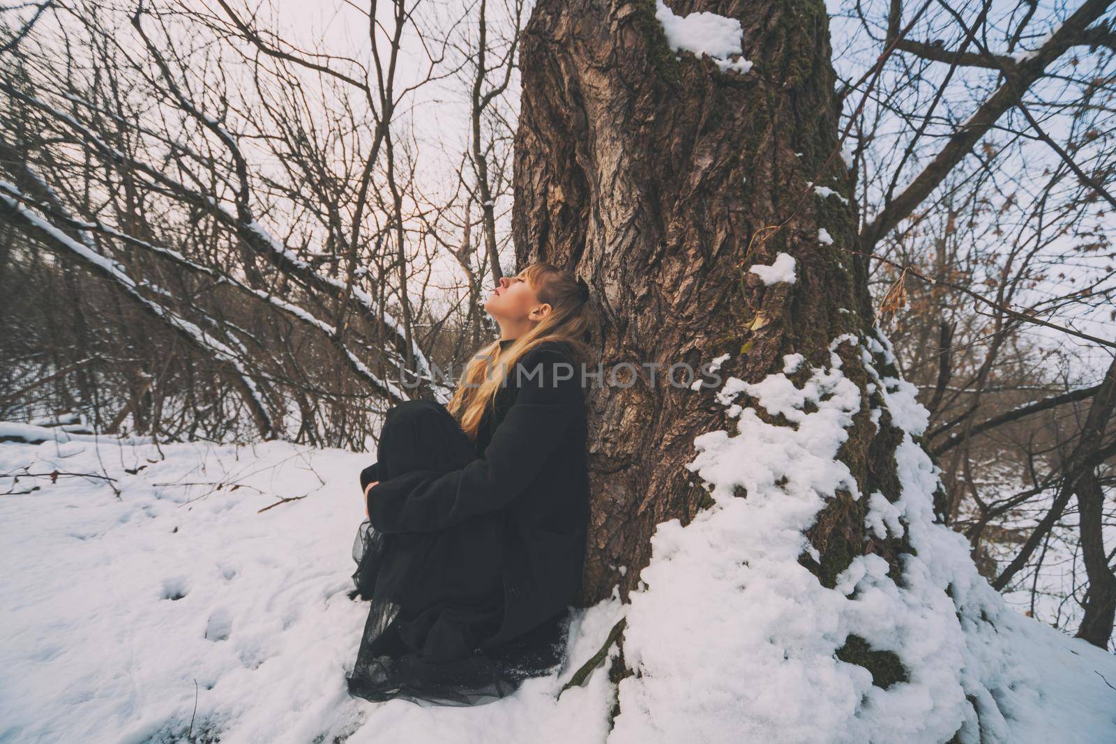 Depressed and lonely woman crying in forest in winter.