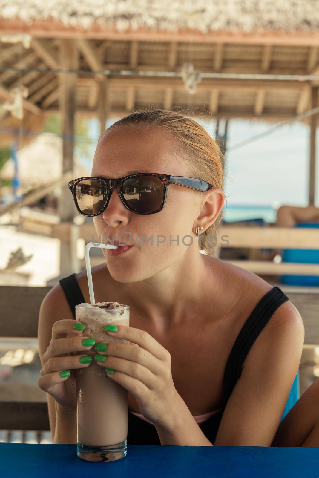 Young woman enjoying milkshake at tropical beach cafe