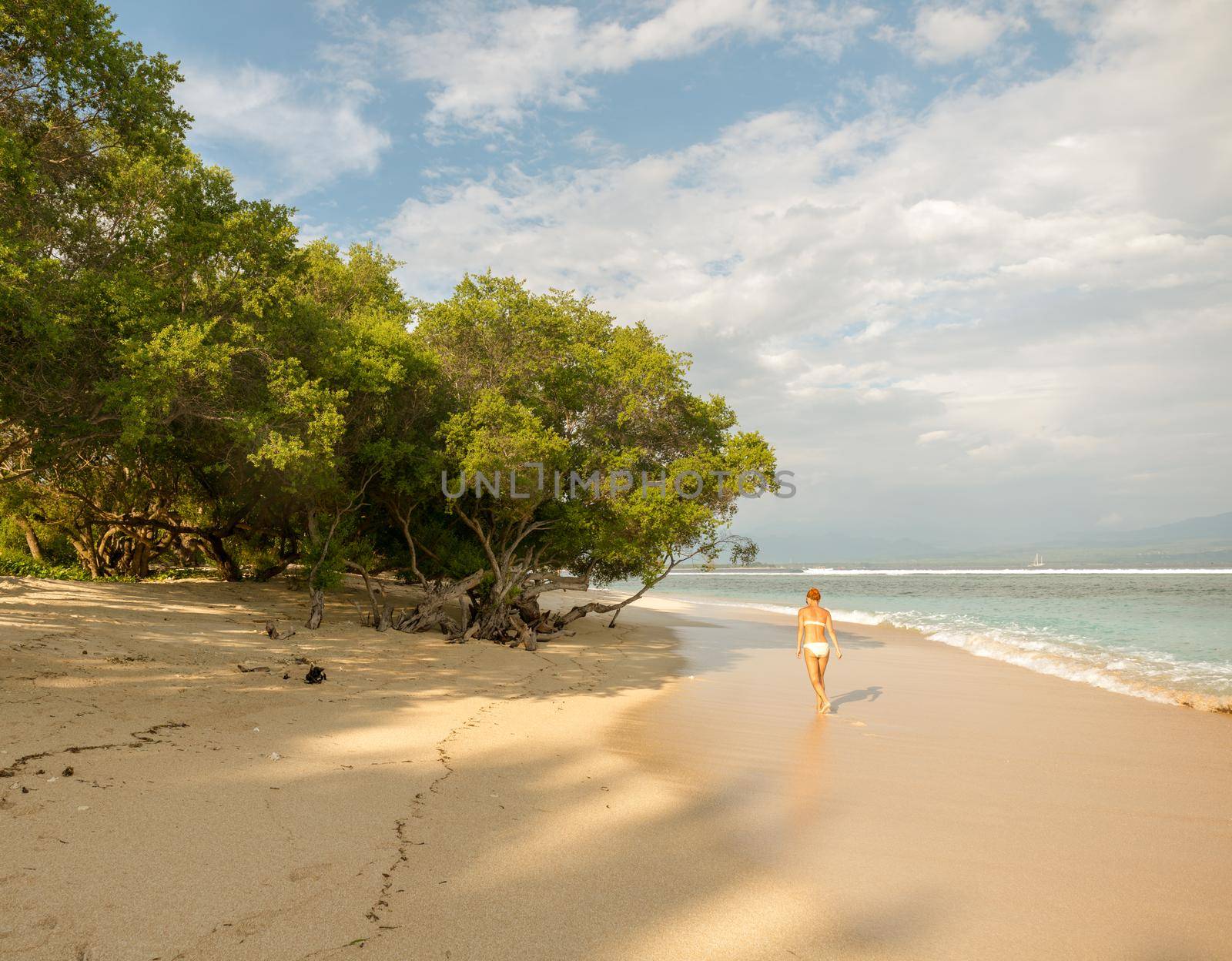 Young woman walking along tropical beach by nikitabuida