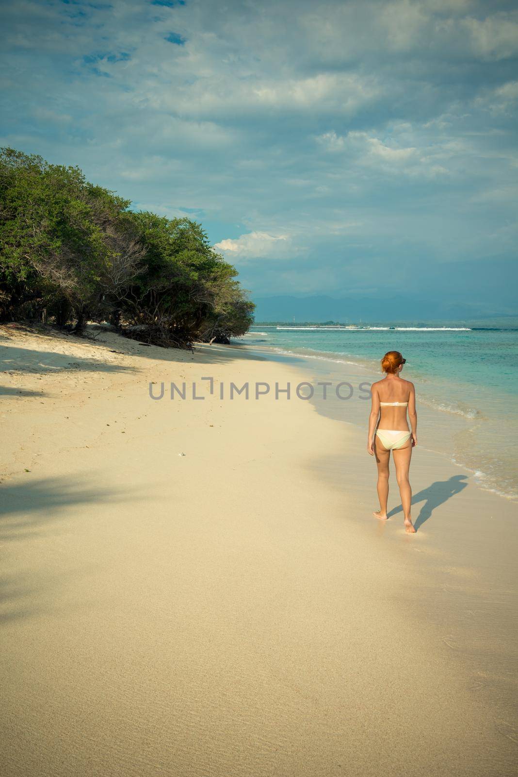 Young woman walking along tropical beach by nikitabuida