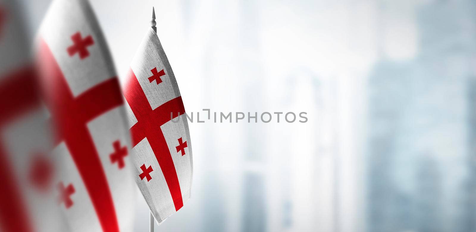 Small flags of Georgia on a blurry background of the city.